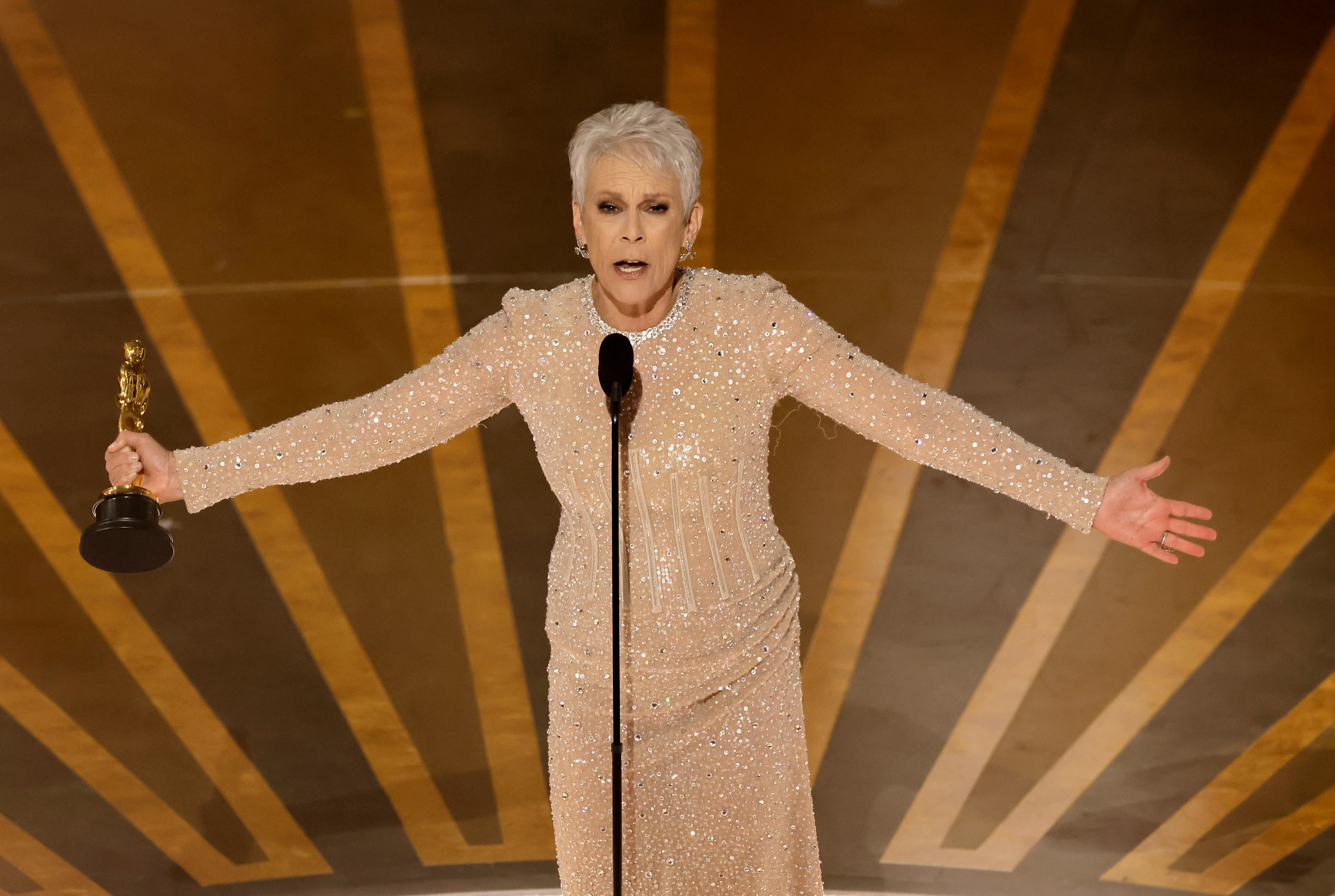 jamie lee curtis reacting with enthusiasm while accepting an academy award onstage