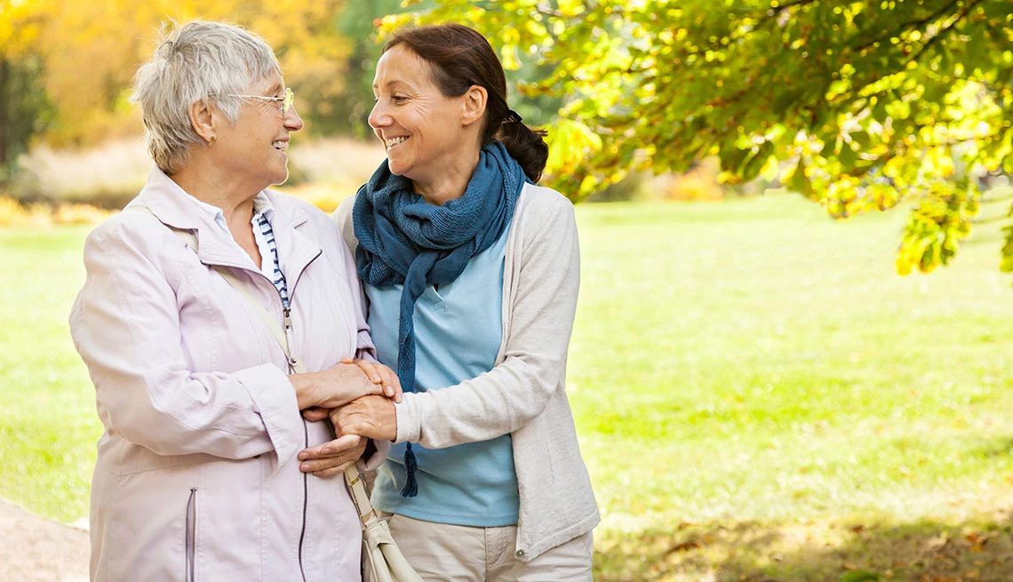 AARP Foundation senior woman and carer walking in the park