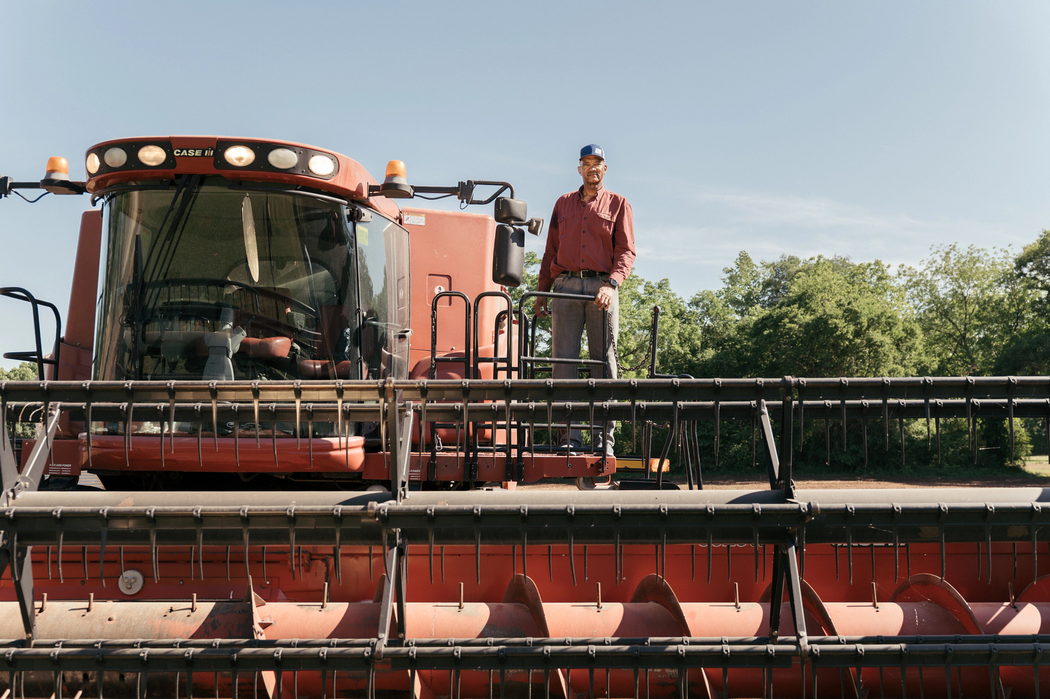 a farmer standing on heavy farm equipment