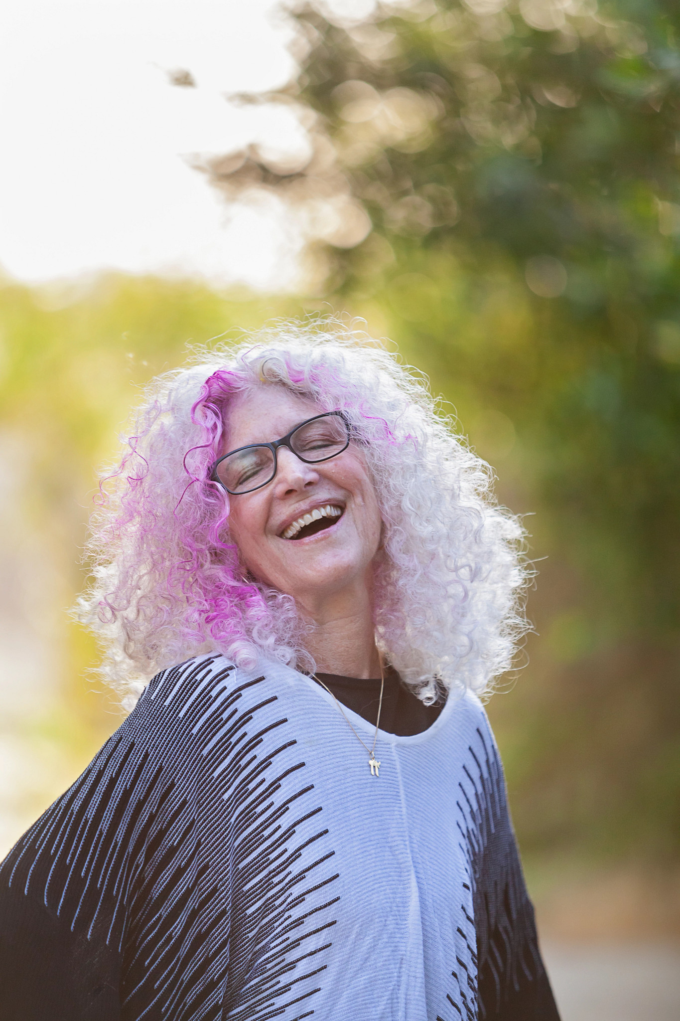 a smiling janie emaus celebrates her head of curly pink streaked white hair