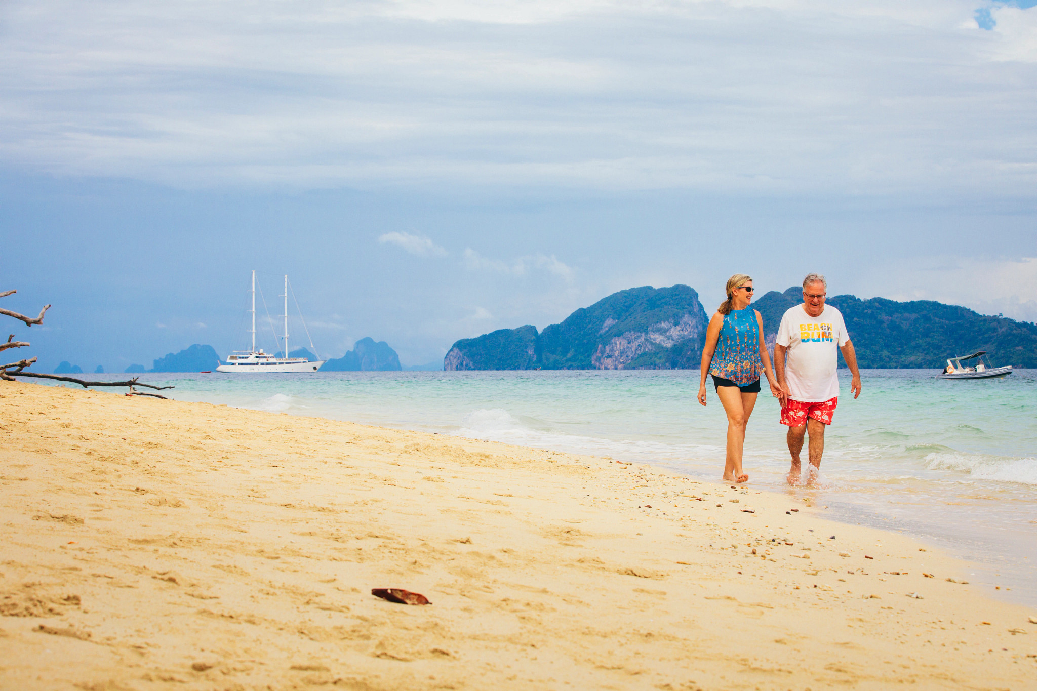 a couple walking through waves splashing ashore on a beach