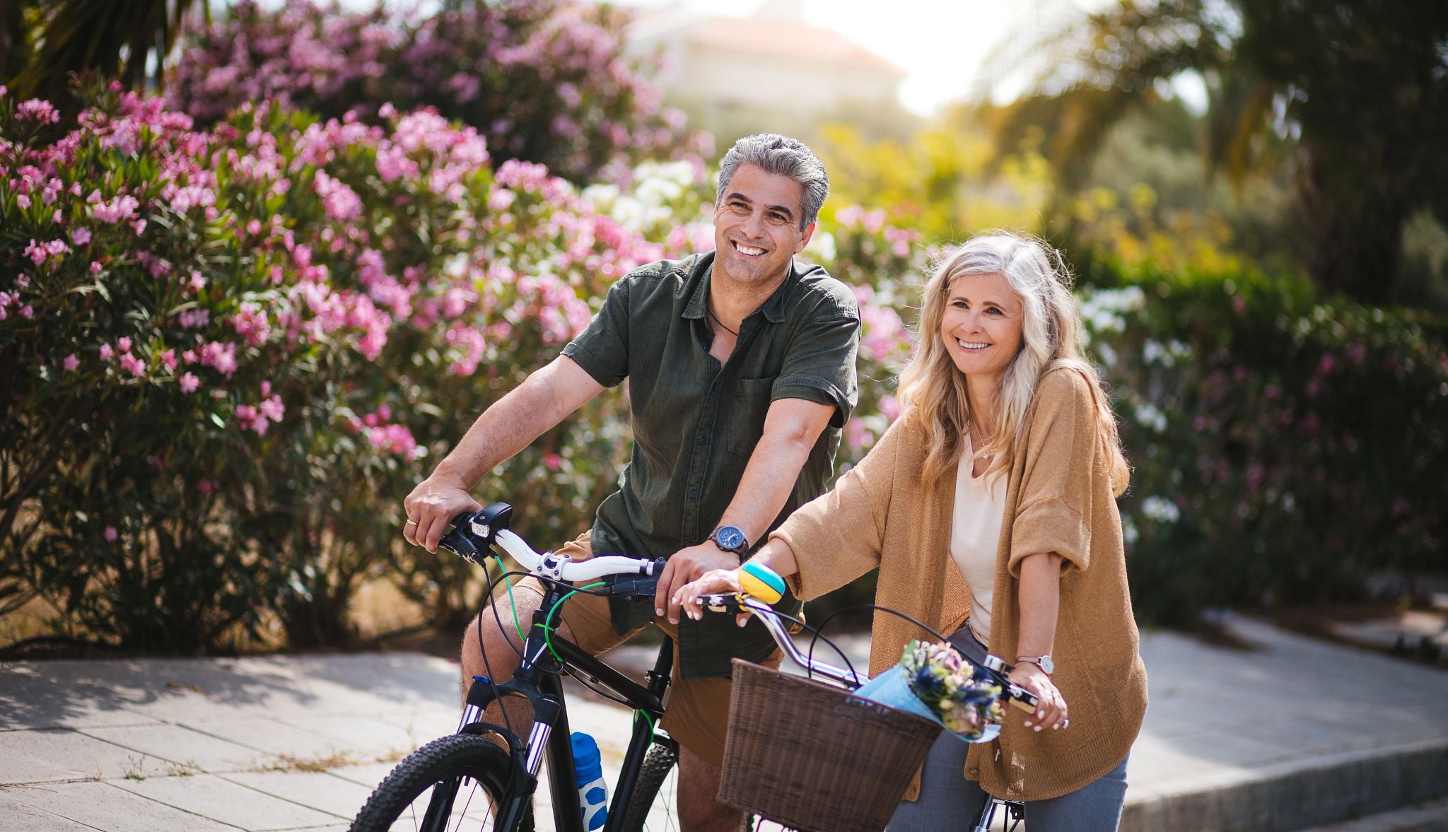 Two people smiling while riding bicycles on a sunny afternoon Two people smiling while riding bicycles on a sunny afternoon