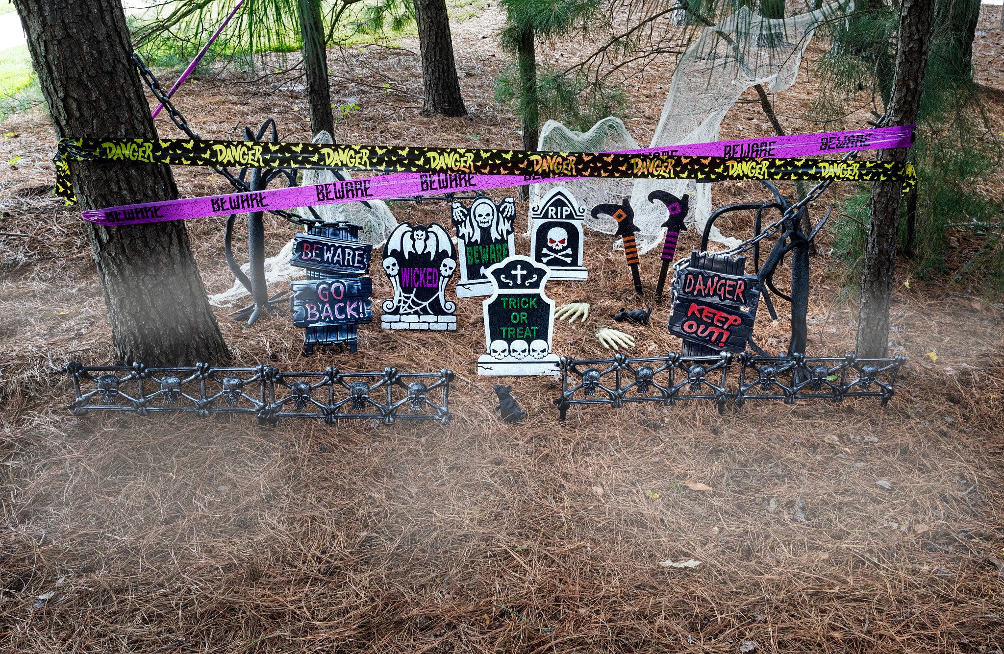 Varios letreros de lápidas falsas y otras decoraciones de Halloween debajo de un árbol