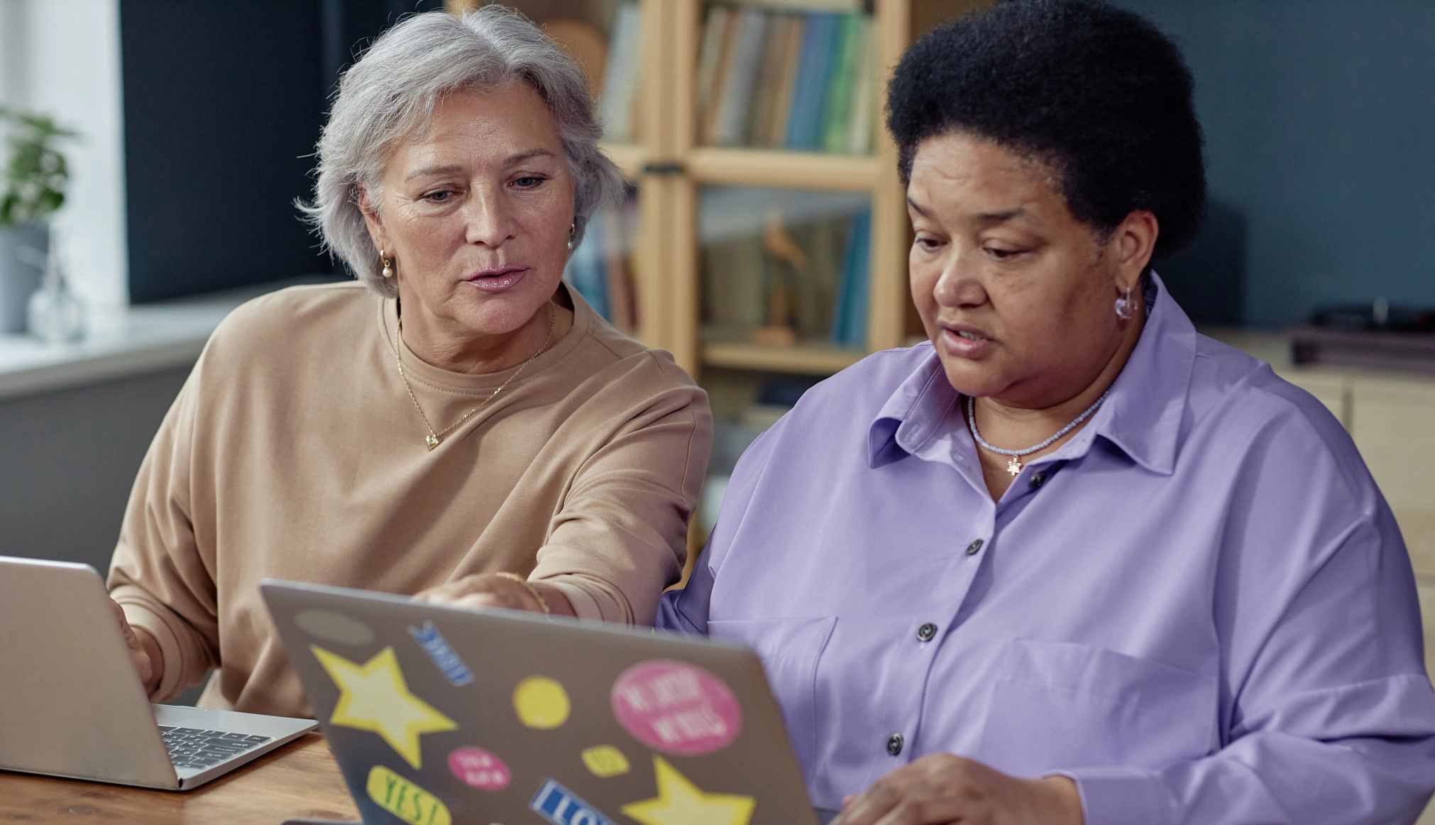 Los estados recibirán fondos para ayudar a los adultos mayores y a otros a acceder a dispositivos y aprender habilidades digitales. Dos mujeres mayores utilizan computadoras portátiles