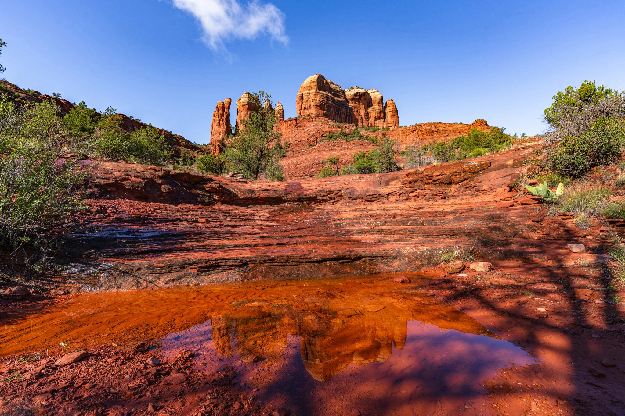 a small pool of water leading up to a large rock formation