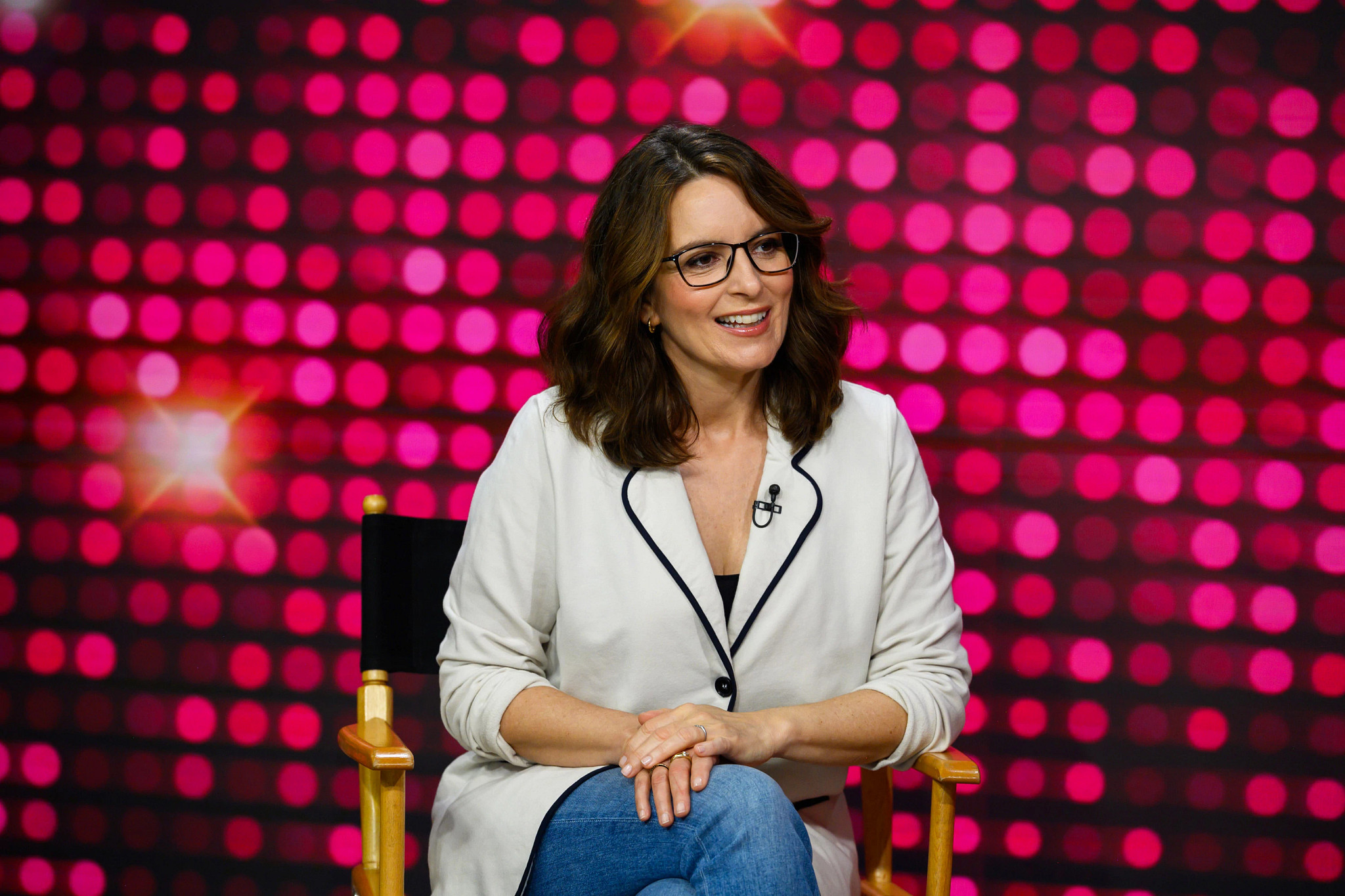 tina fey speaking while seated in front of a studio background