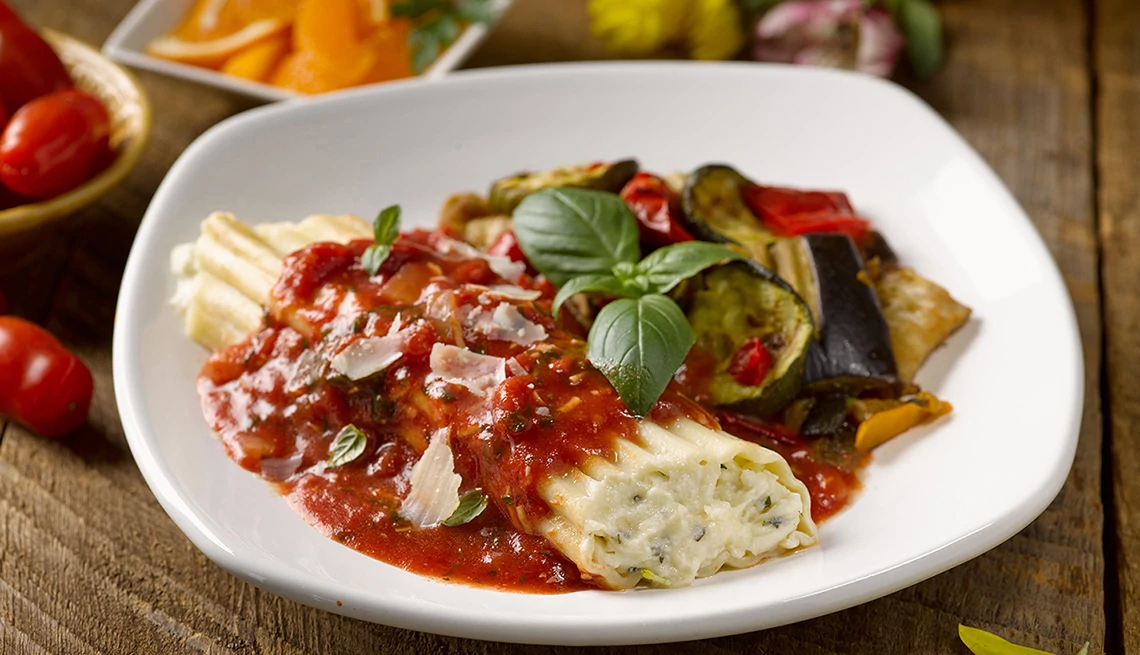 Un plato de pasta con queso, tomate y vegetales Un plato de pasta con queso, tomate y vegetales