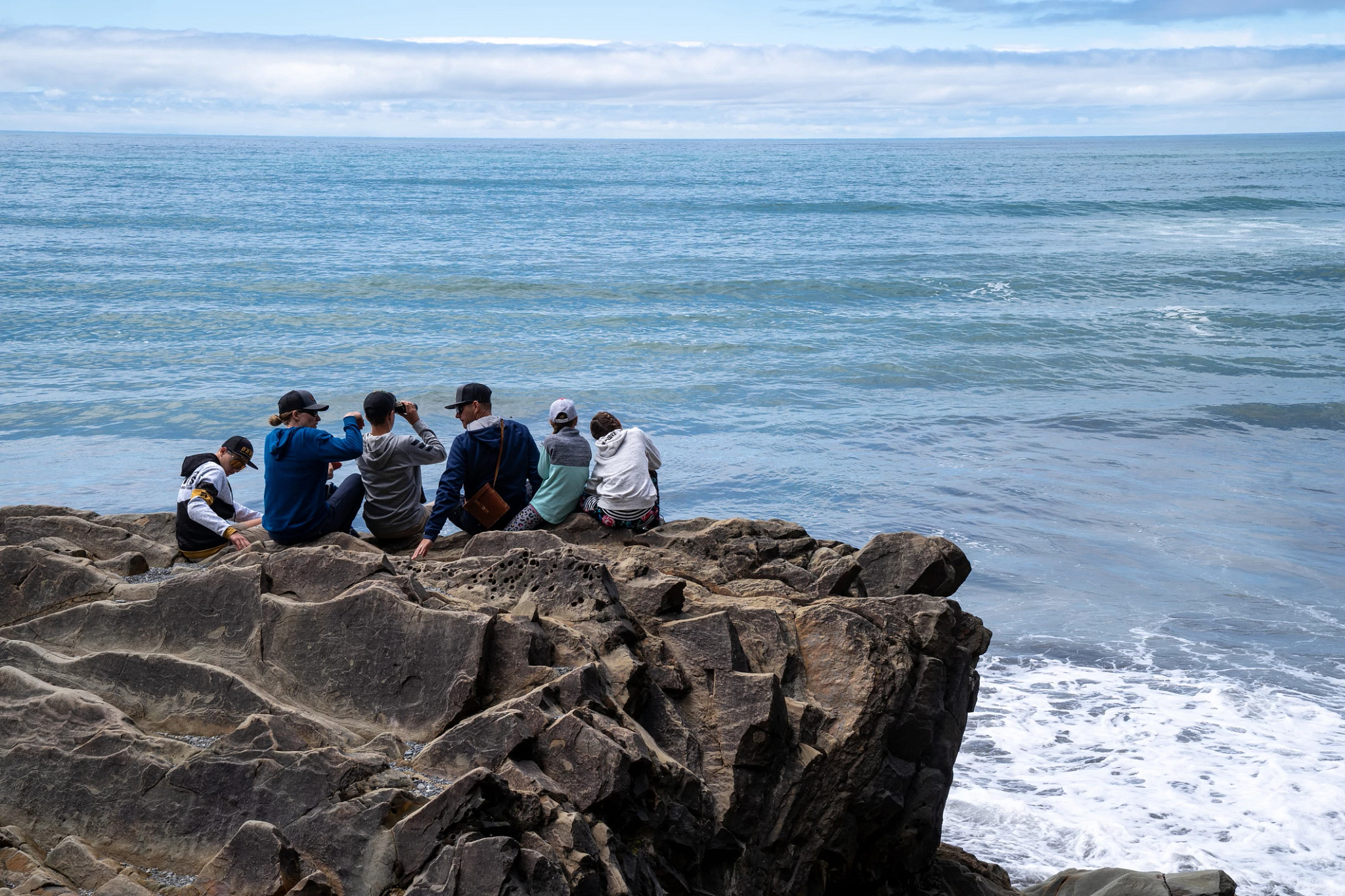people sitting on a rock near the ocean