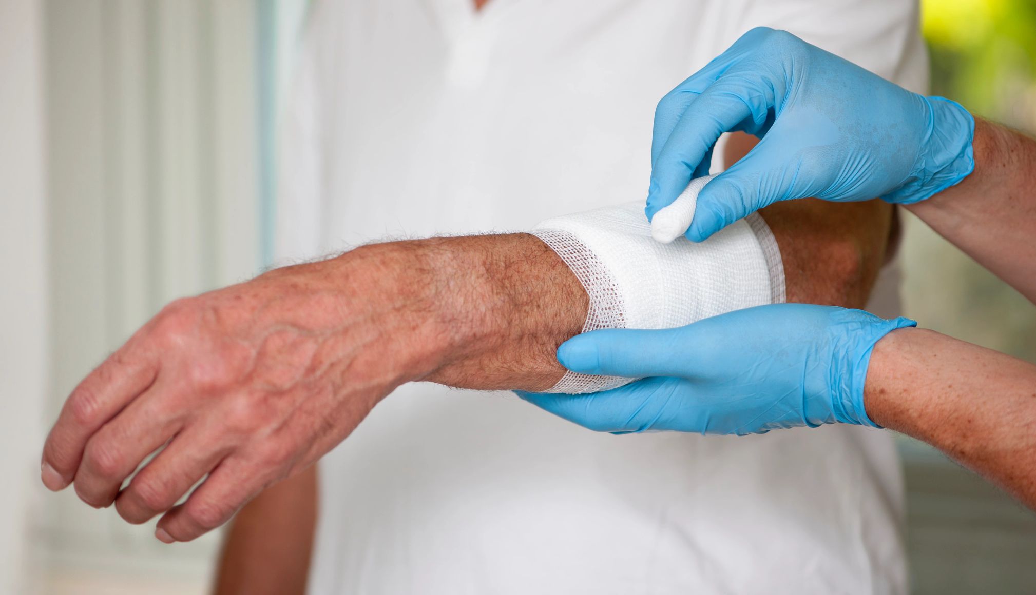 What to know about wound care hands wearing gloves bandage an older adult's arm