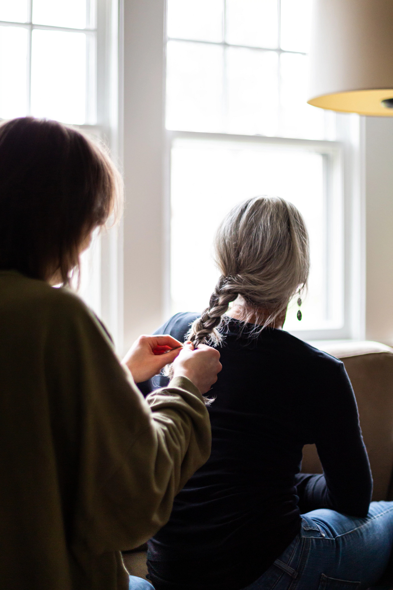 A photo shows a child braiding their mother’s hair