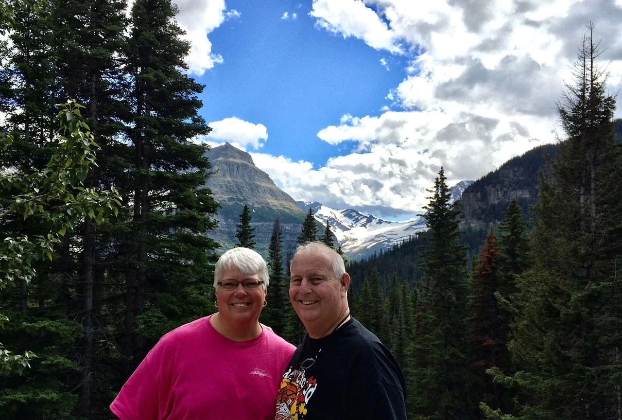 patricia and marlyn washburn in front of trees and mountains at glacier national park