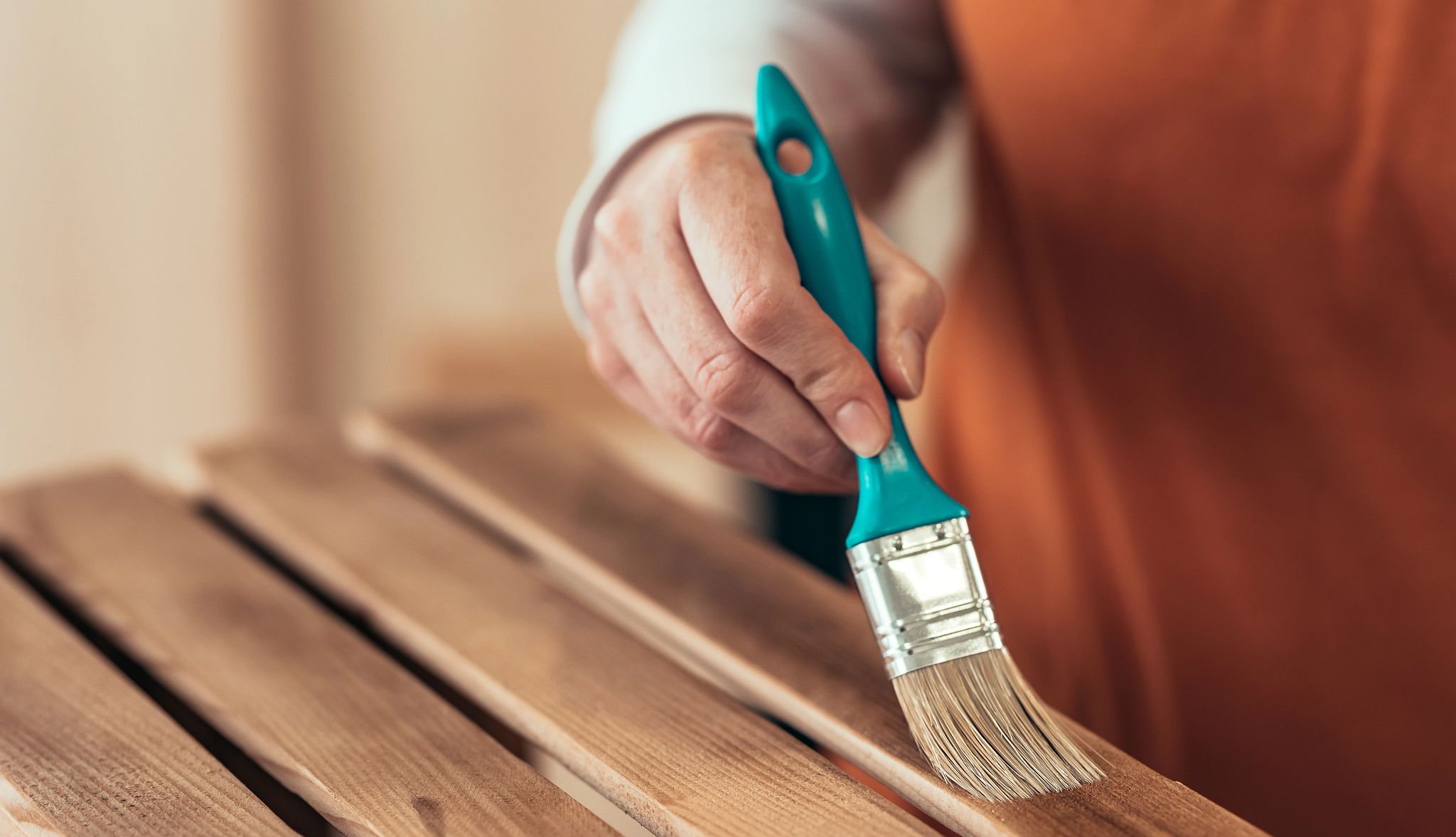 Care for your thrifted goods Person varnishing wooden crate