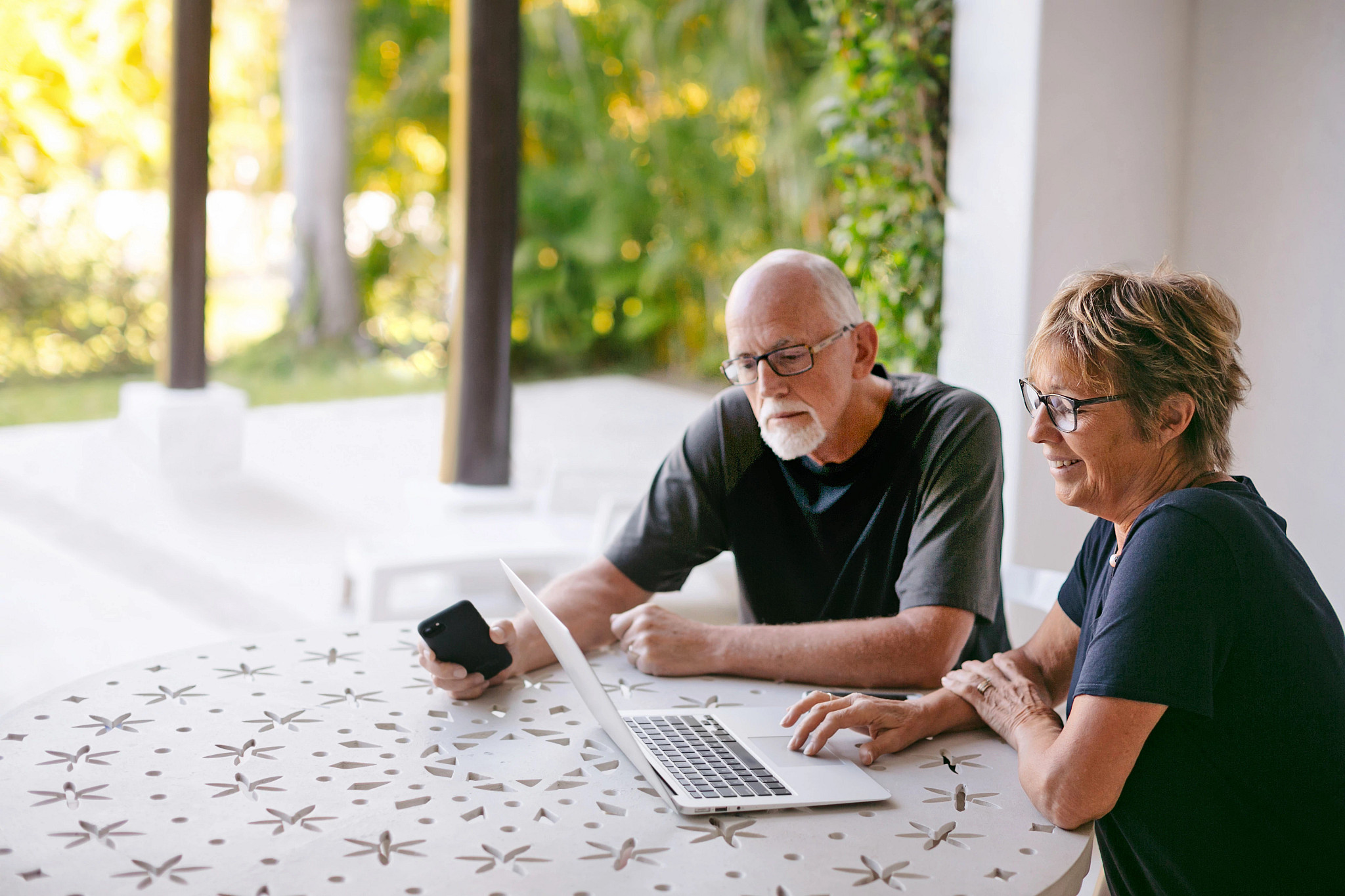 a couple sitting at a table looking at a laptop computer