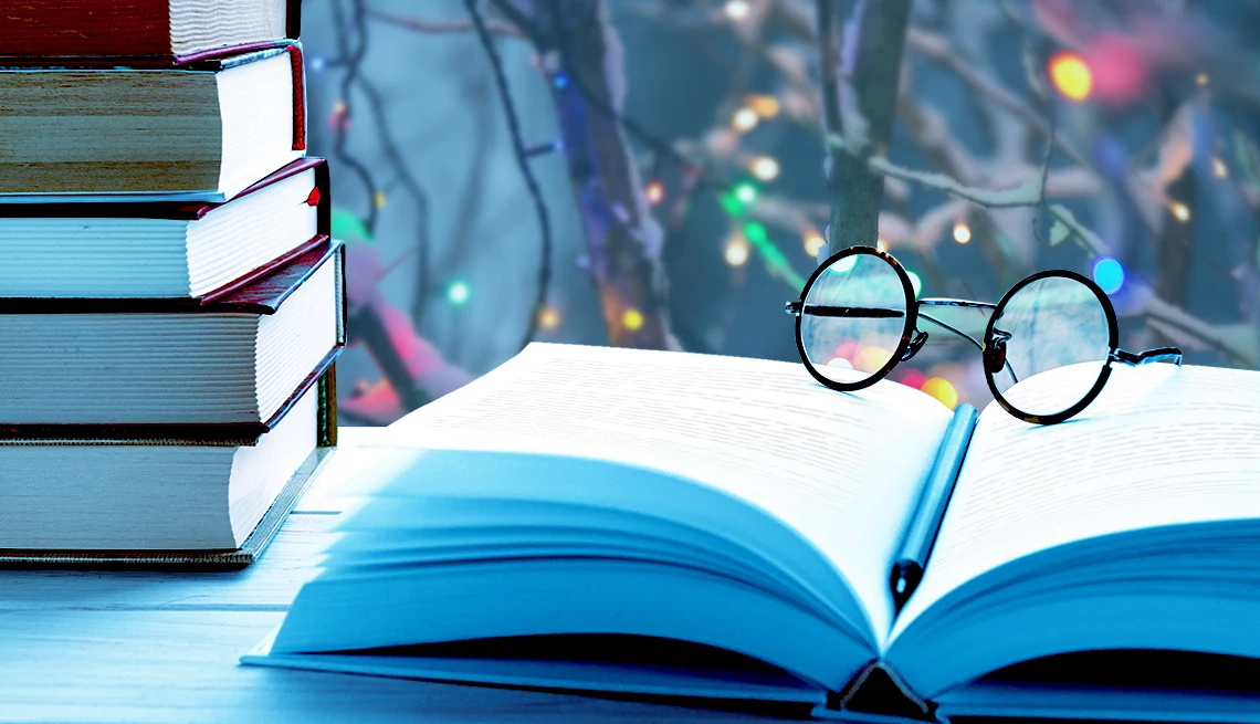 Holiday Mysteries books stacked with glasses on top and christmas lights