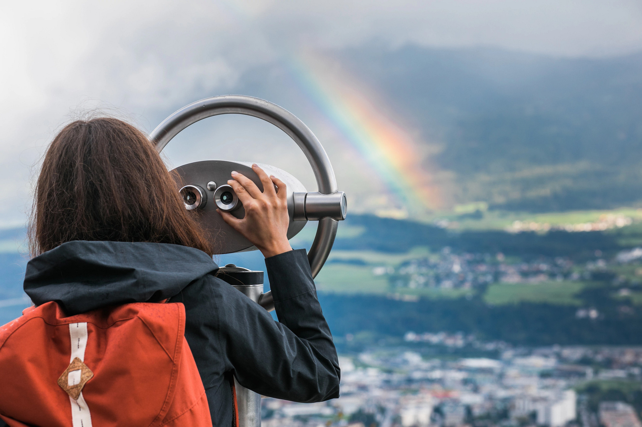 Woman looking through tower viewer at a rainbow