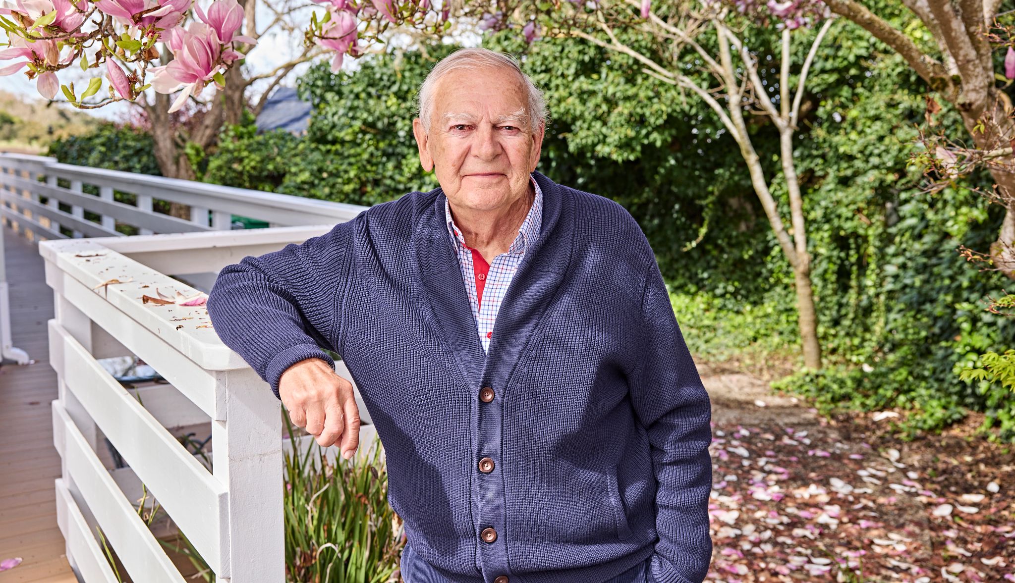 Don Johanson leaning up against white fence with trees behind him