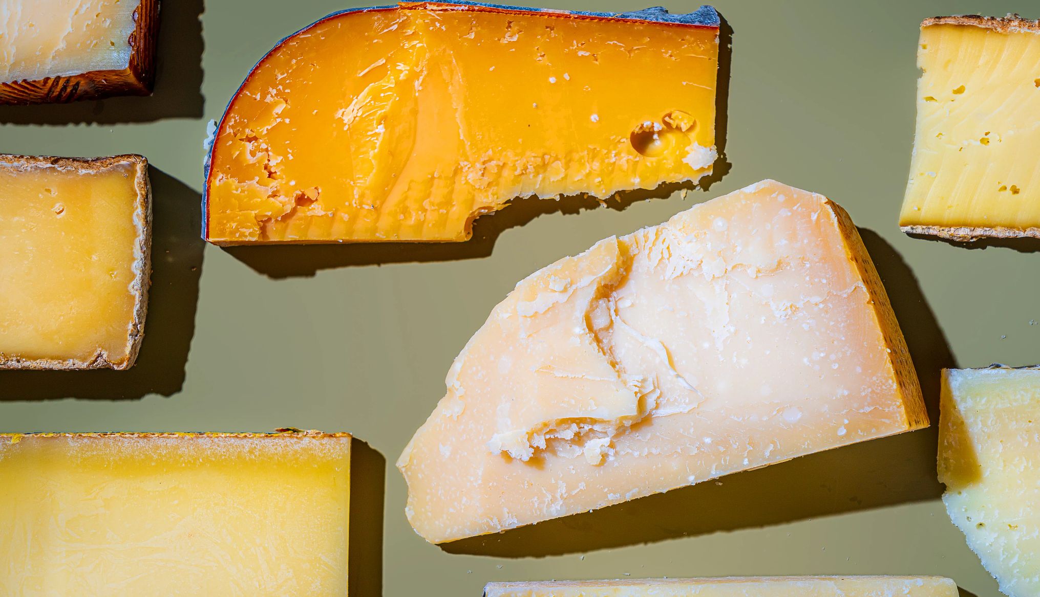 various hard cheese on a green background