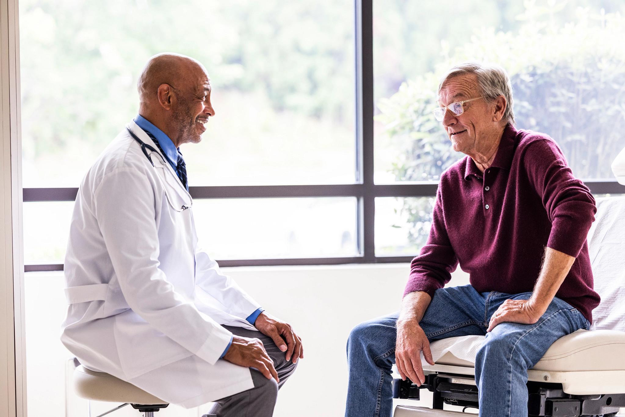 A male doctor talking with a male patient in an exam room