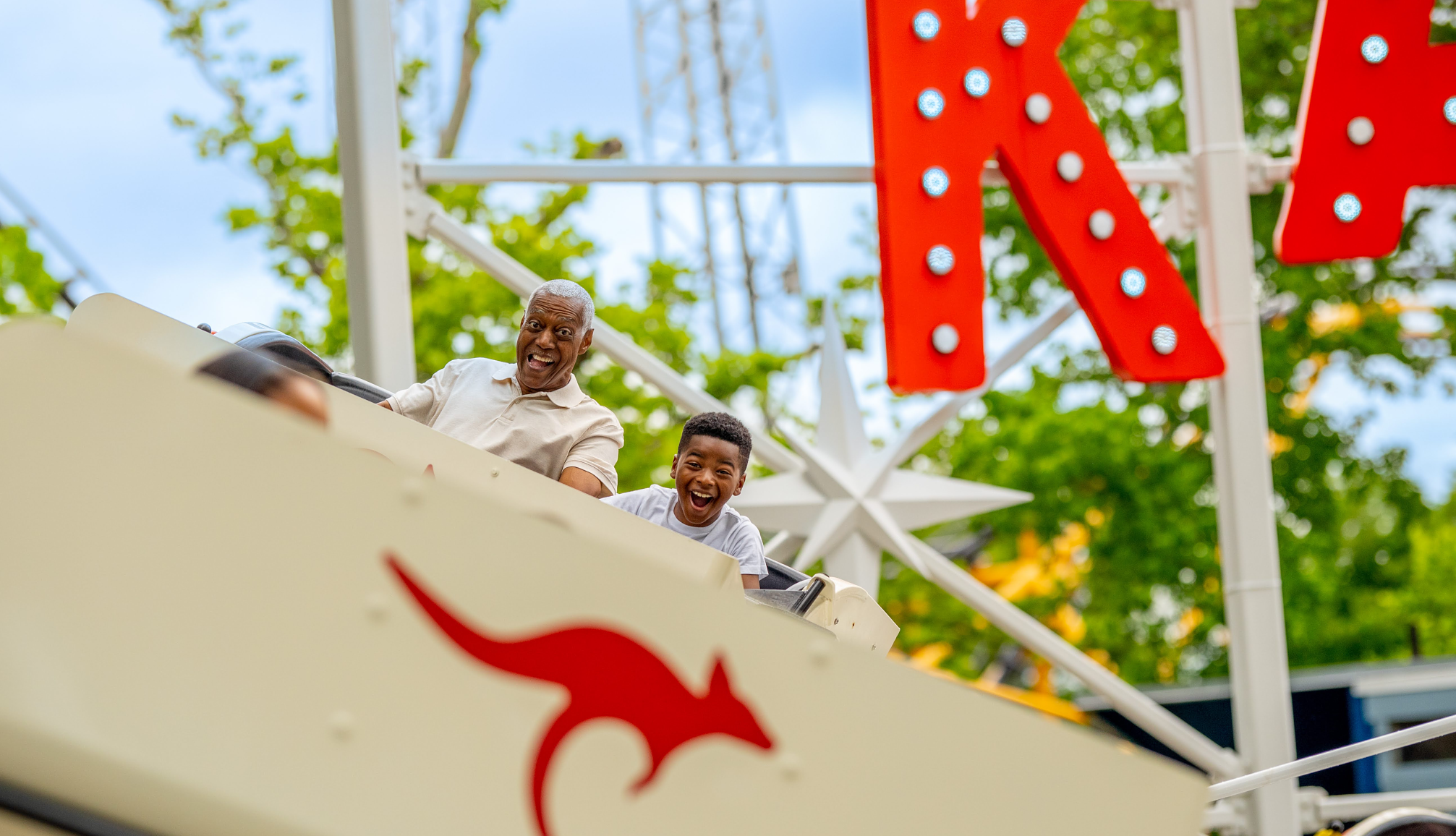 Parques de atracciones clásicos y de ambiente familiar para visitar a cualquier edad Un abuelo y su nieto en una atracción de un parque de atracciones