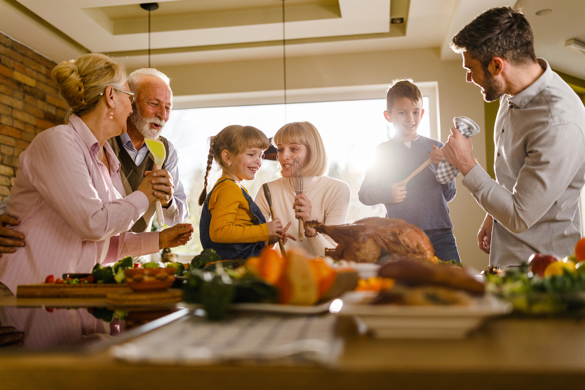 Happy multi-generation family having fun while singing during Thanksgiving day in the kitchen.
