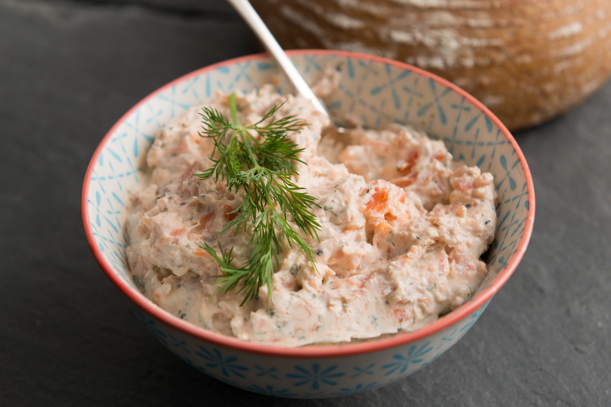 Bowl of creamy salmon spread topped with fresh dill
