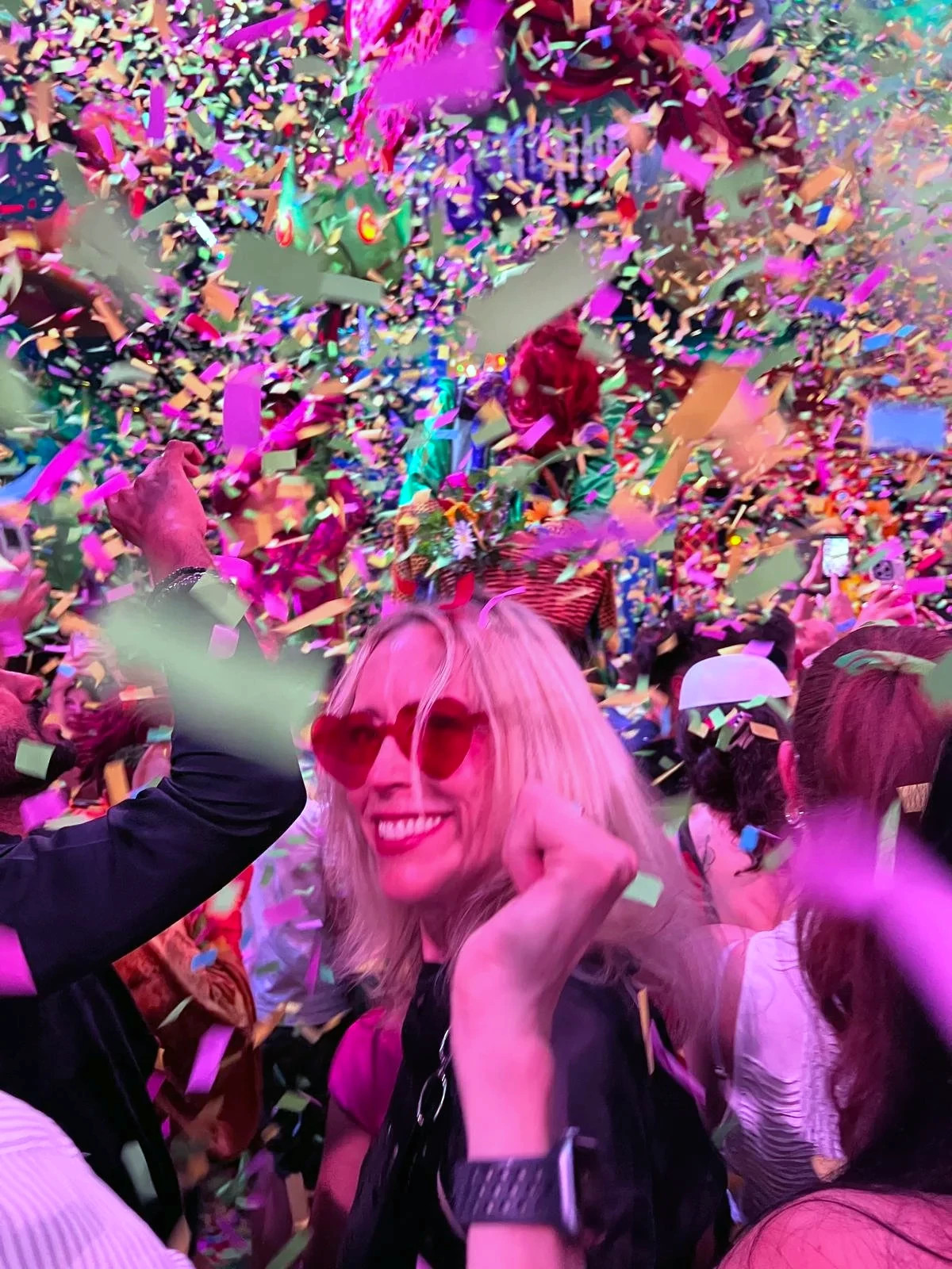 Tina Woods smiling and dancing at a club around other people with confetti falling