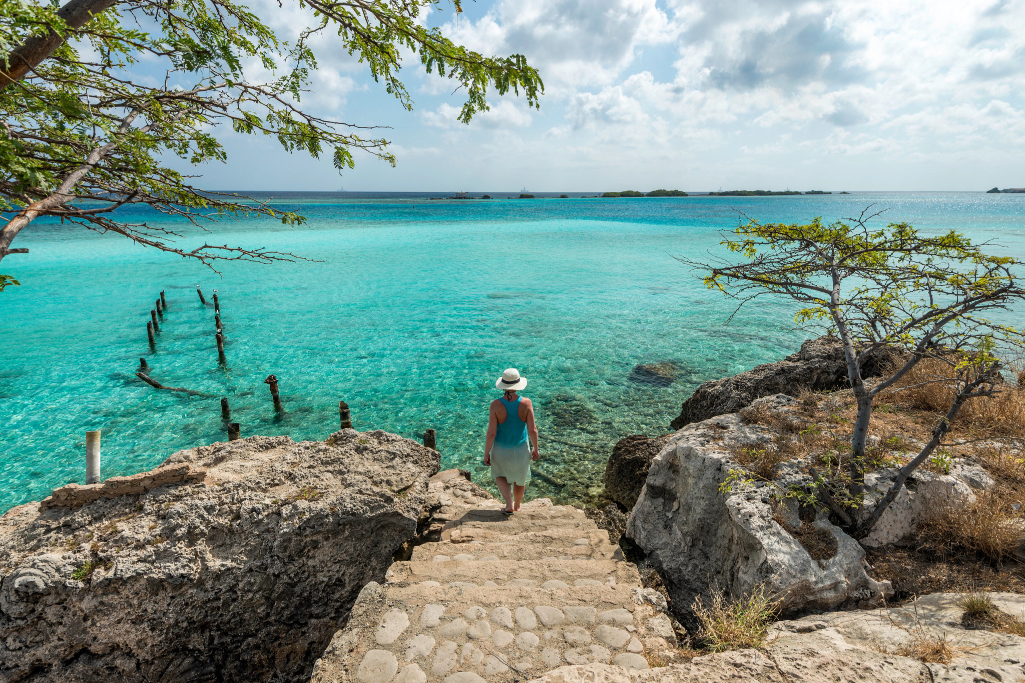 a person walking down steps that leads to the ocean in Aruba
