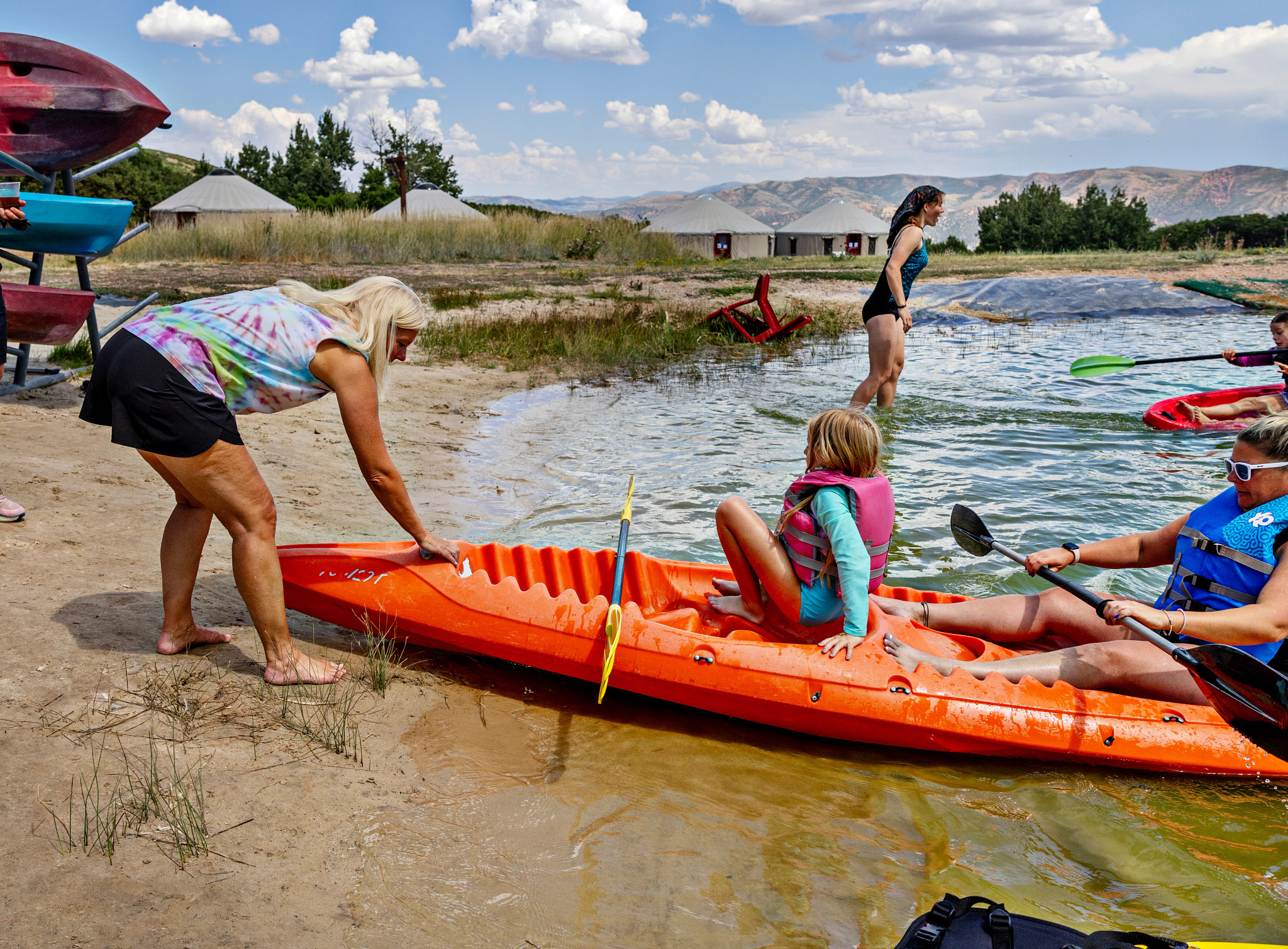 A photo shows Lynne Hughes helping a child maneuver a canoe into lake at Comfort Zone Camp.