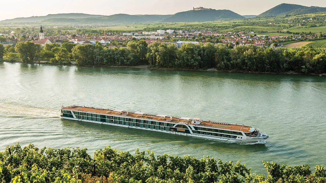 river cruise ship, wide river, tress, city