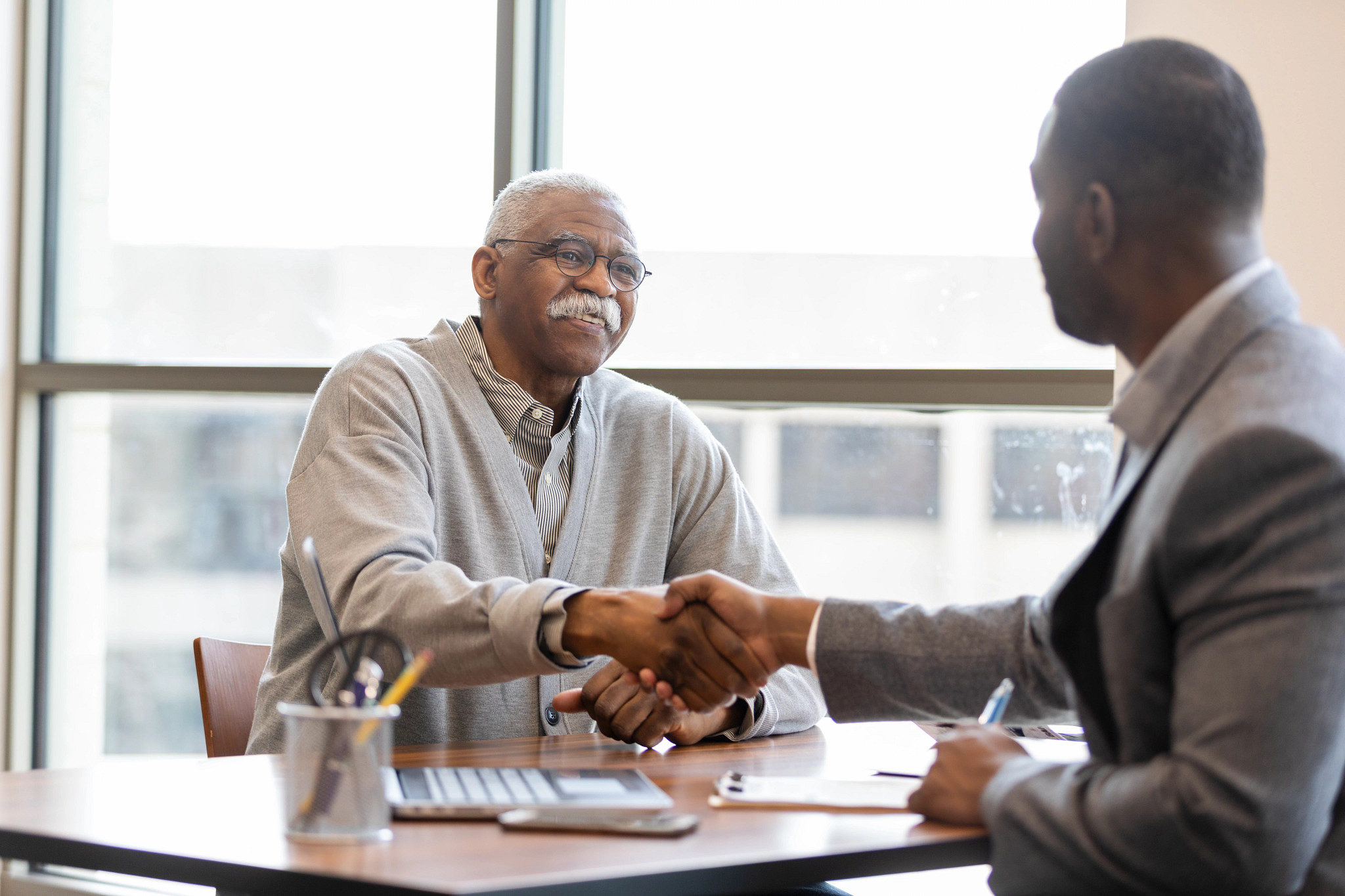 Two businessmen shaking hands and sealing a deal in a professional office setting