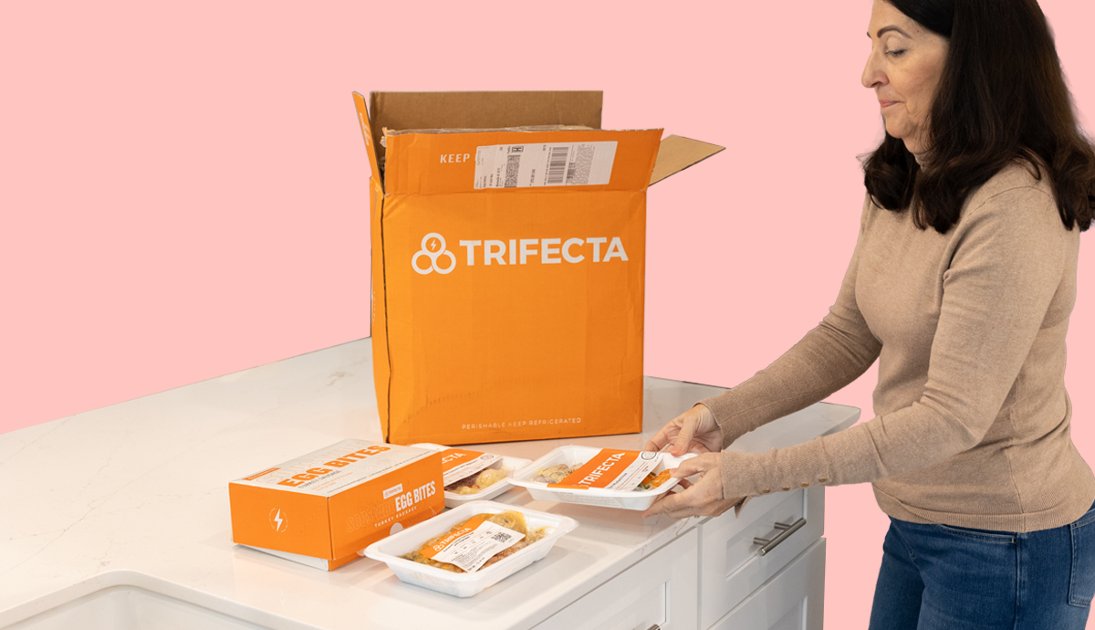 An older adult woman unpacking her Trifecta prepared meal box.