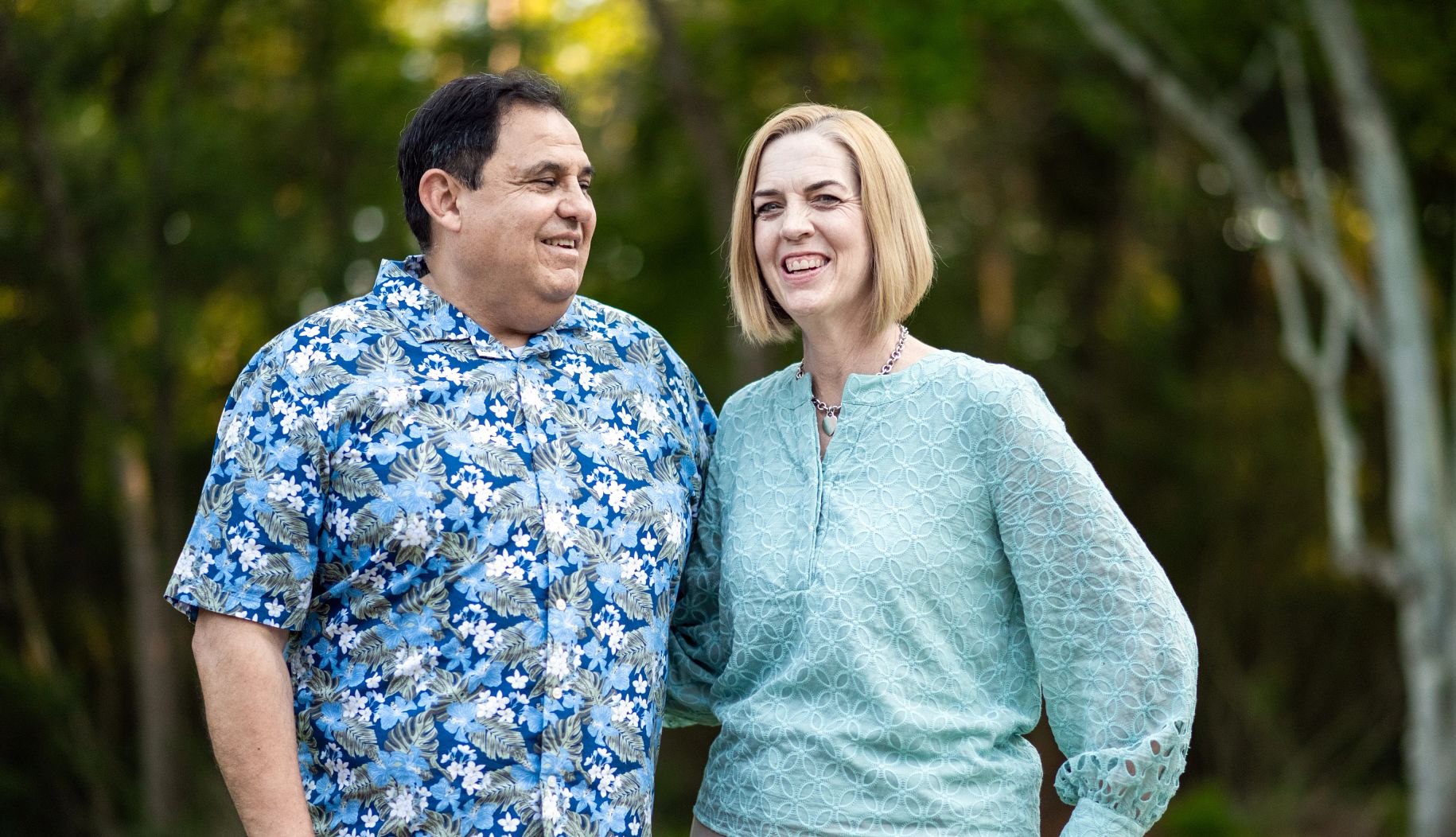 jaime and donna tovalin, both wearing printed shirts, smile for a portrait outside.