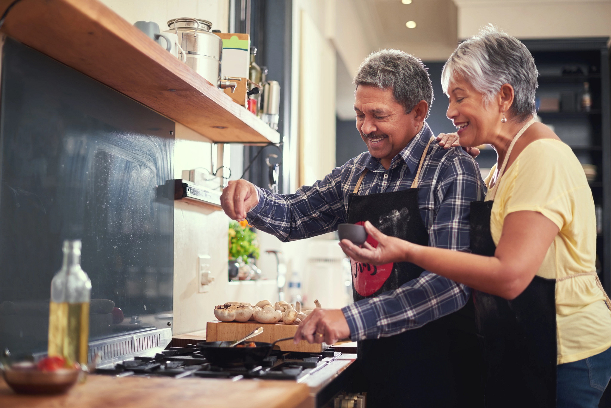 Shot of a happy mature couple adding salt to a dish while cooking together at home