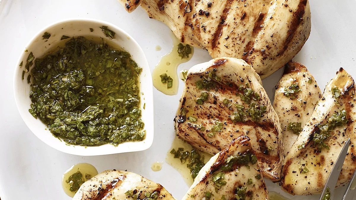 A close-up view of chicken breast with basil-mint sauce