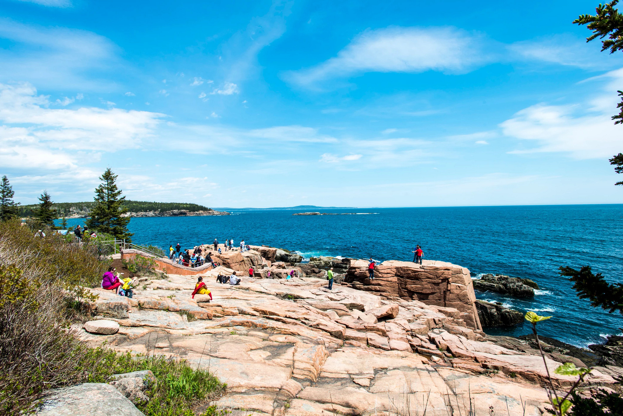 People on giant rock surface with the ocean in the background