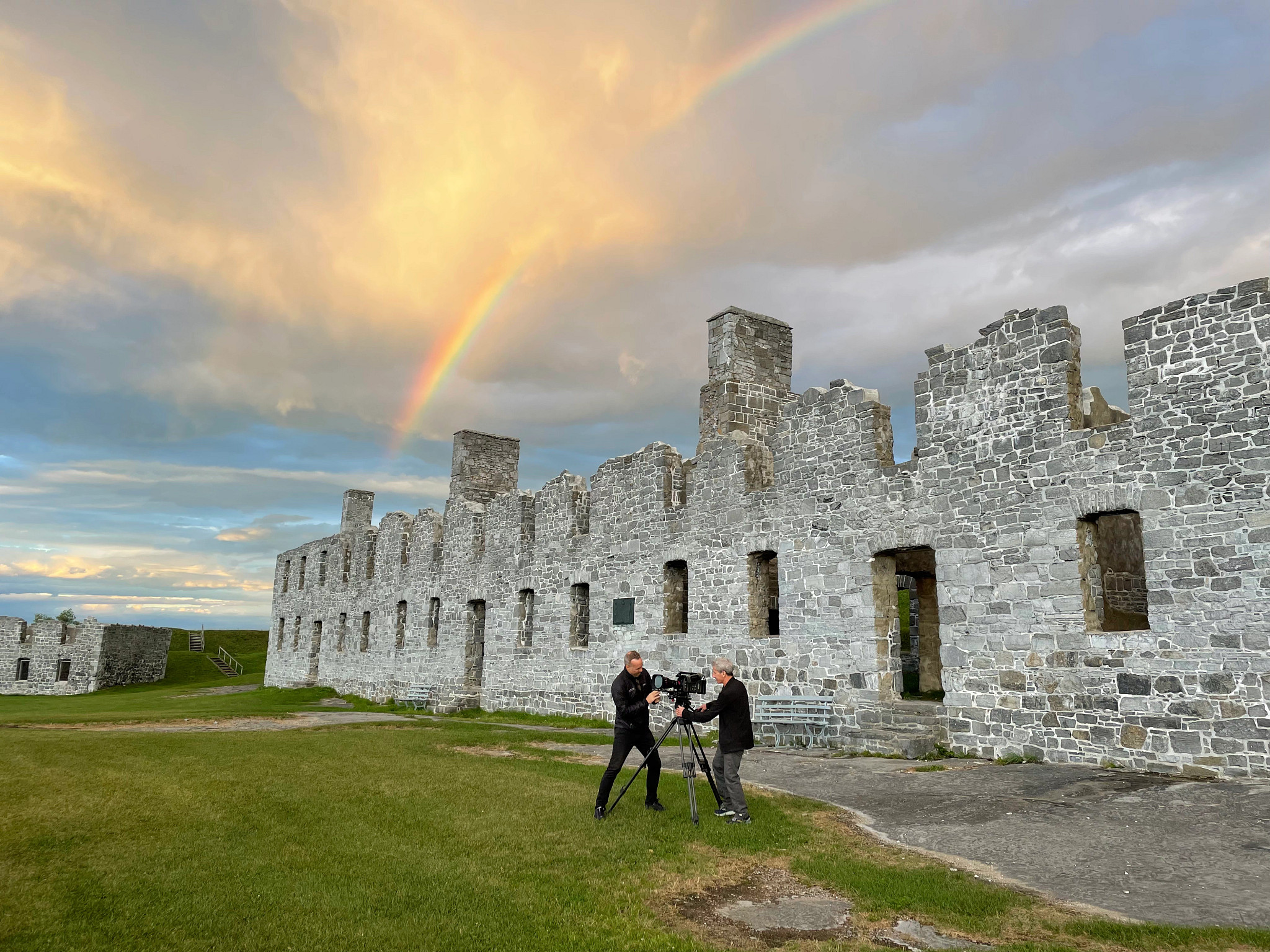 the crew of the documentary the american revolution setting up a camera outside a historic fort with a rainbow in the background