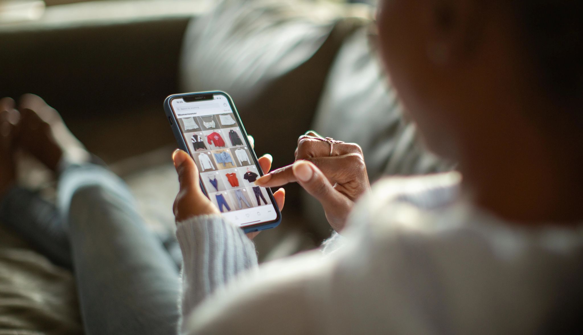 What to know about thrifting online Woman looking at clothes on cell phone