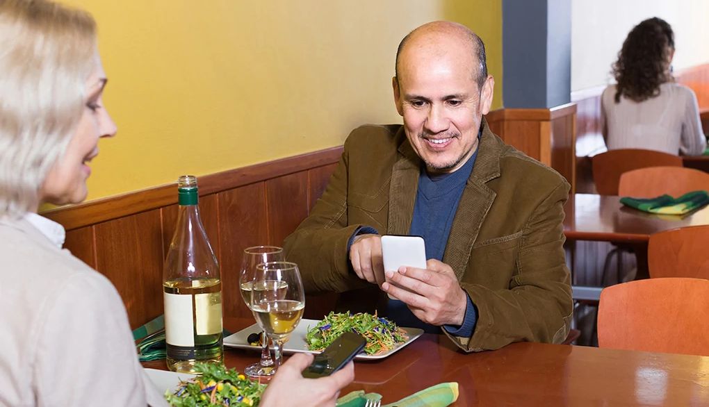 A smartphone notification can distract you from what you're doing in the moment Man and woman distracted by cell phones at a restaurant