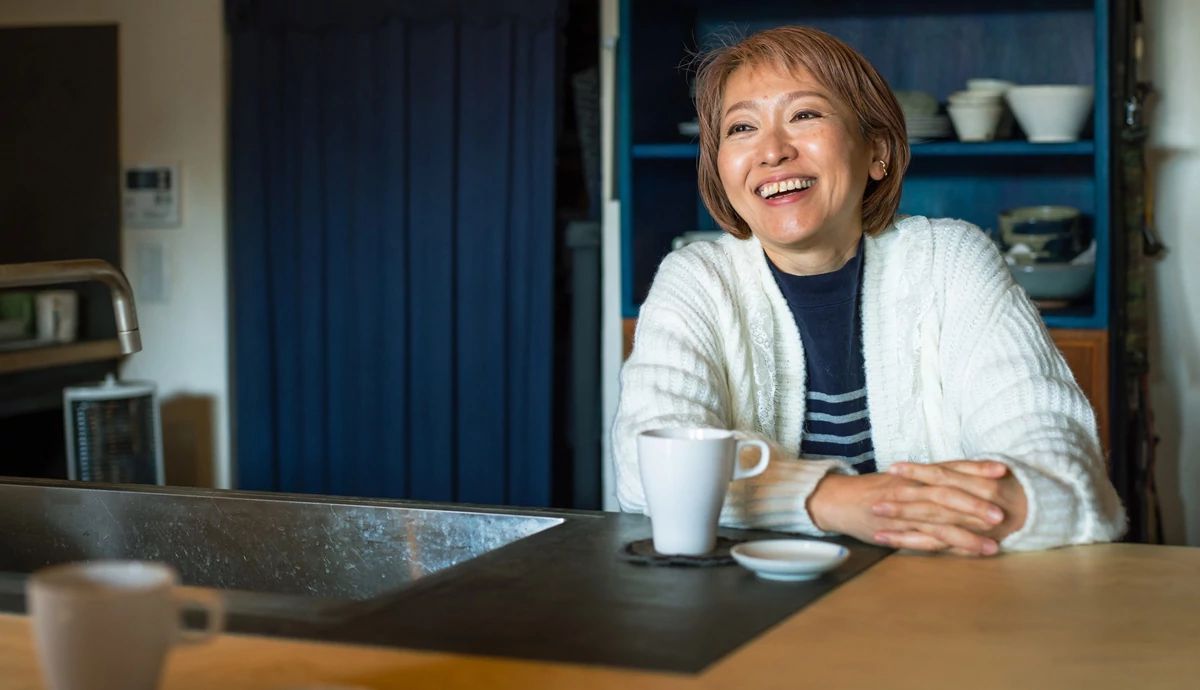 A woman smiling and enjoying coffee and conversation. 