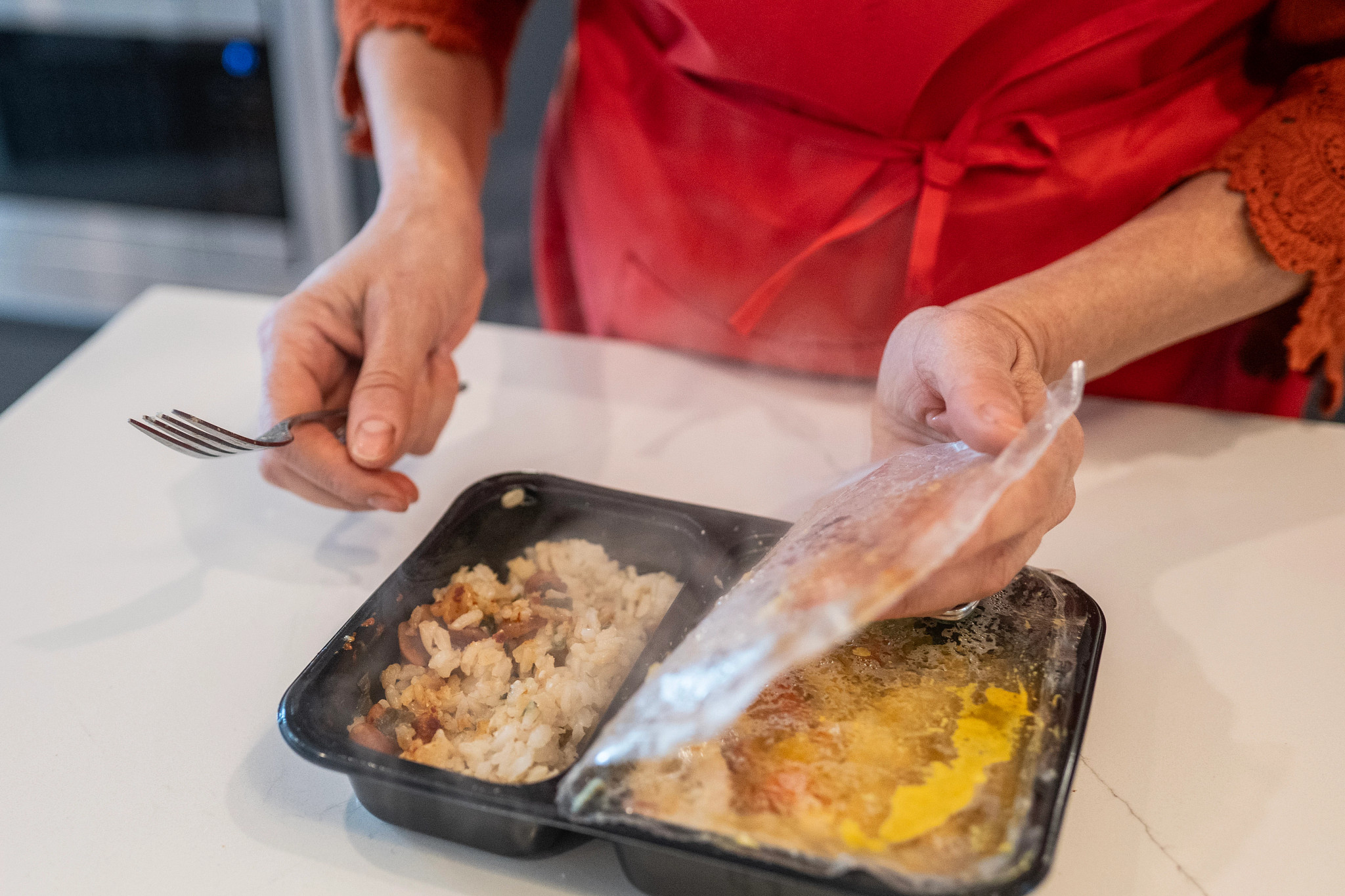 An older adult tester peeling back the plastic on her Factor prepared meal.