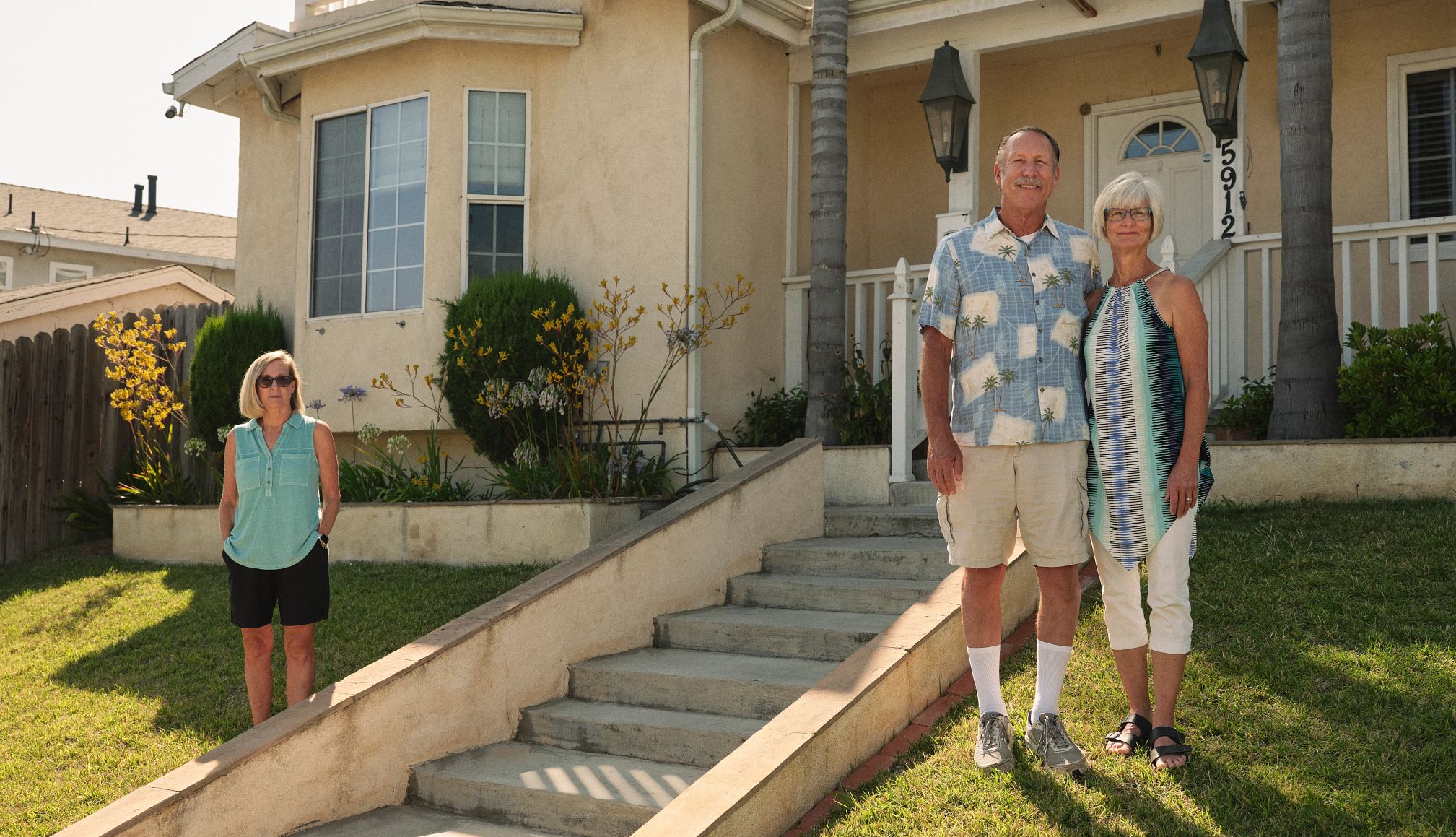 co-owners stand on either side of a set of stairs outside their home