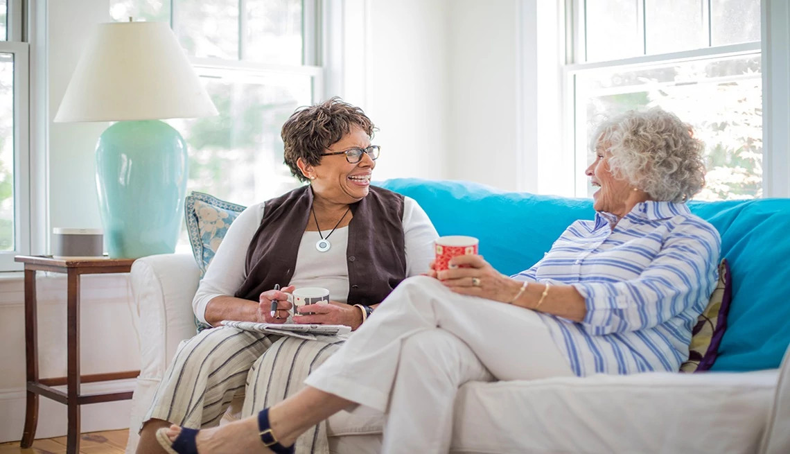Mature women sitting on a sofa together in a bright living room
