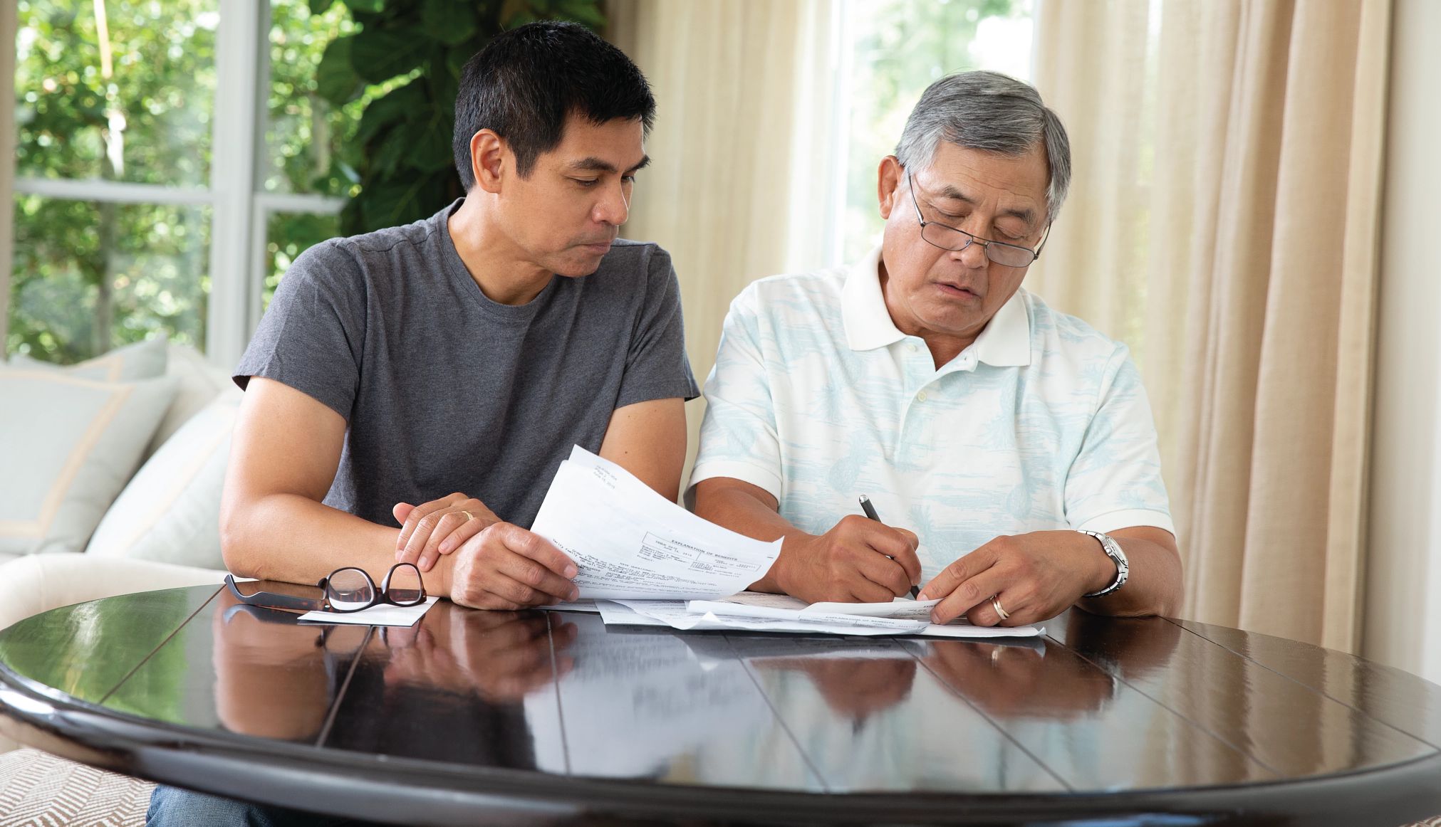 Legal checklist for caregivers older parent and adult child sit at a table and fill out paperwork