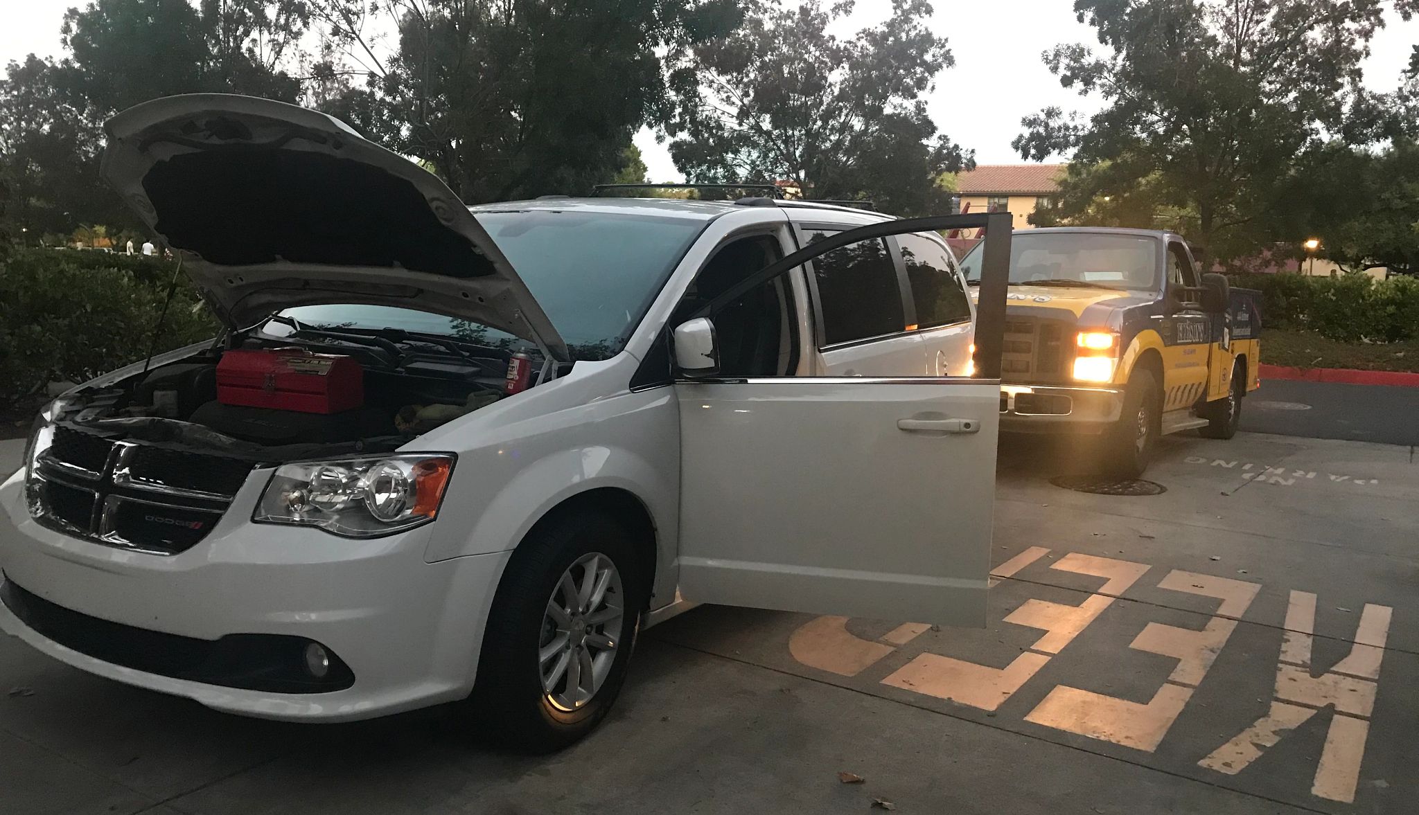 Van trouble after dropping son off at college White van with front hood and driver's side door open; black and yellow pickup truck behind it