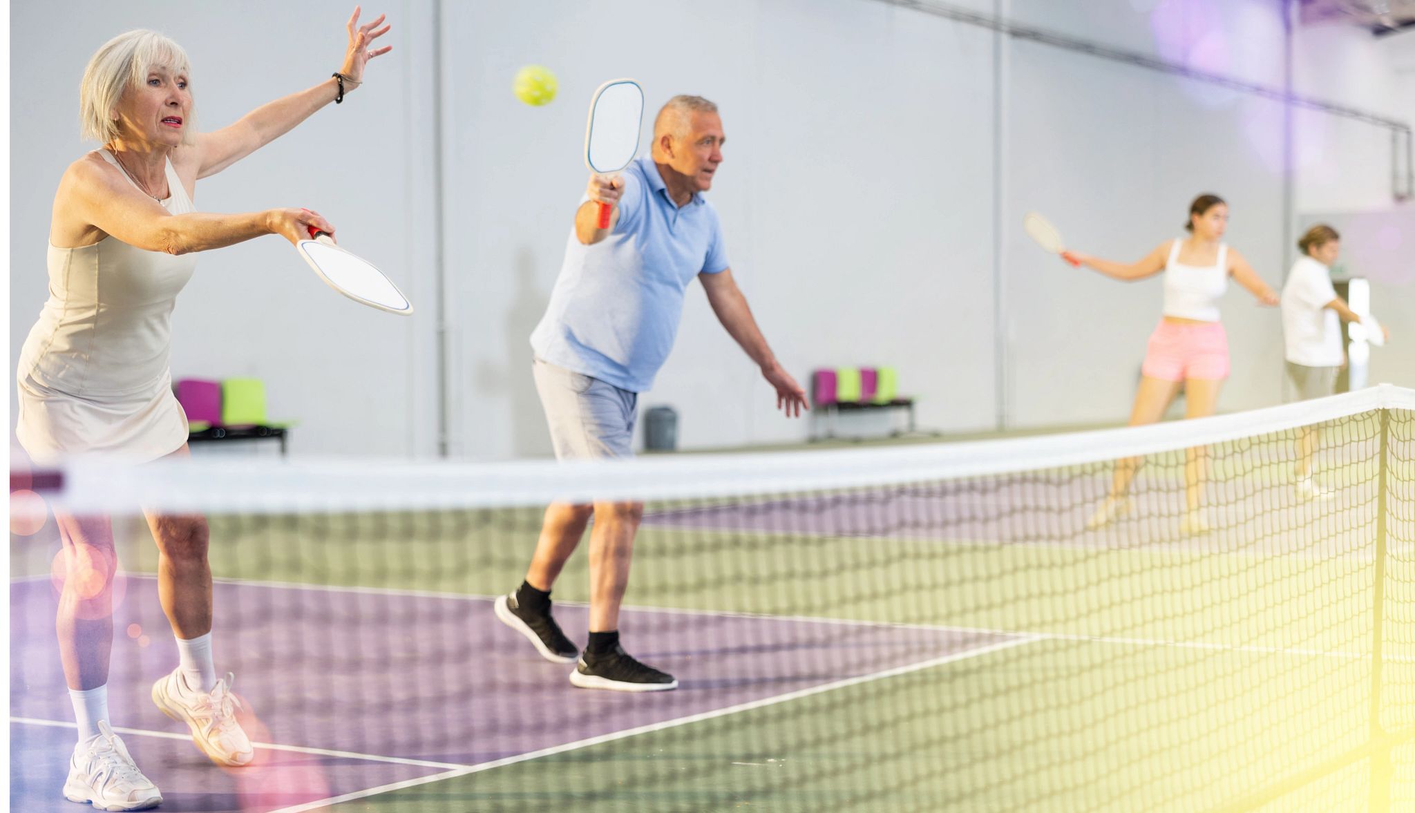 A woman and a man are practicing pickleball in an indoor court - others are in the background practicing as well A woman and a man are practicing pickleball in an indoor court - others are in the background practicing as well