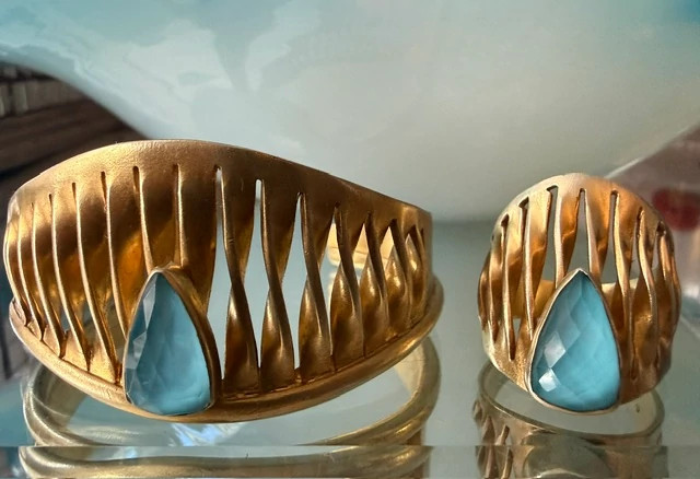A gold arm cuff and ring set, each with a large blue stone.