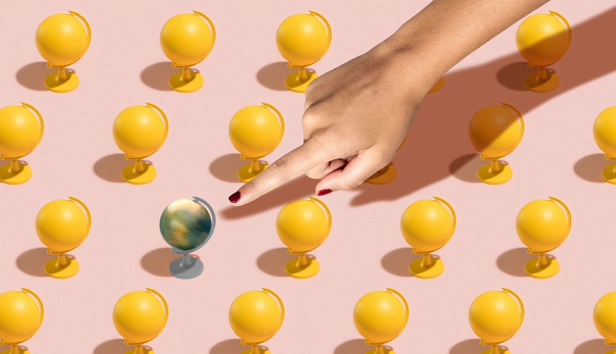 Ilustración de un dedo que señala un globo terráqueo entre muchos otros de color amarillo