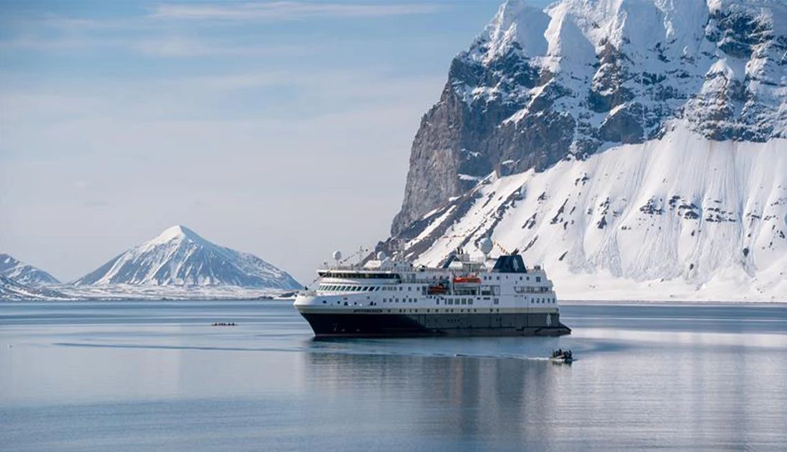 HX Expeditions Cruise ship in the Arctic with breathtaking views of snowy mountains in the background