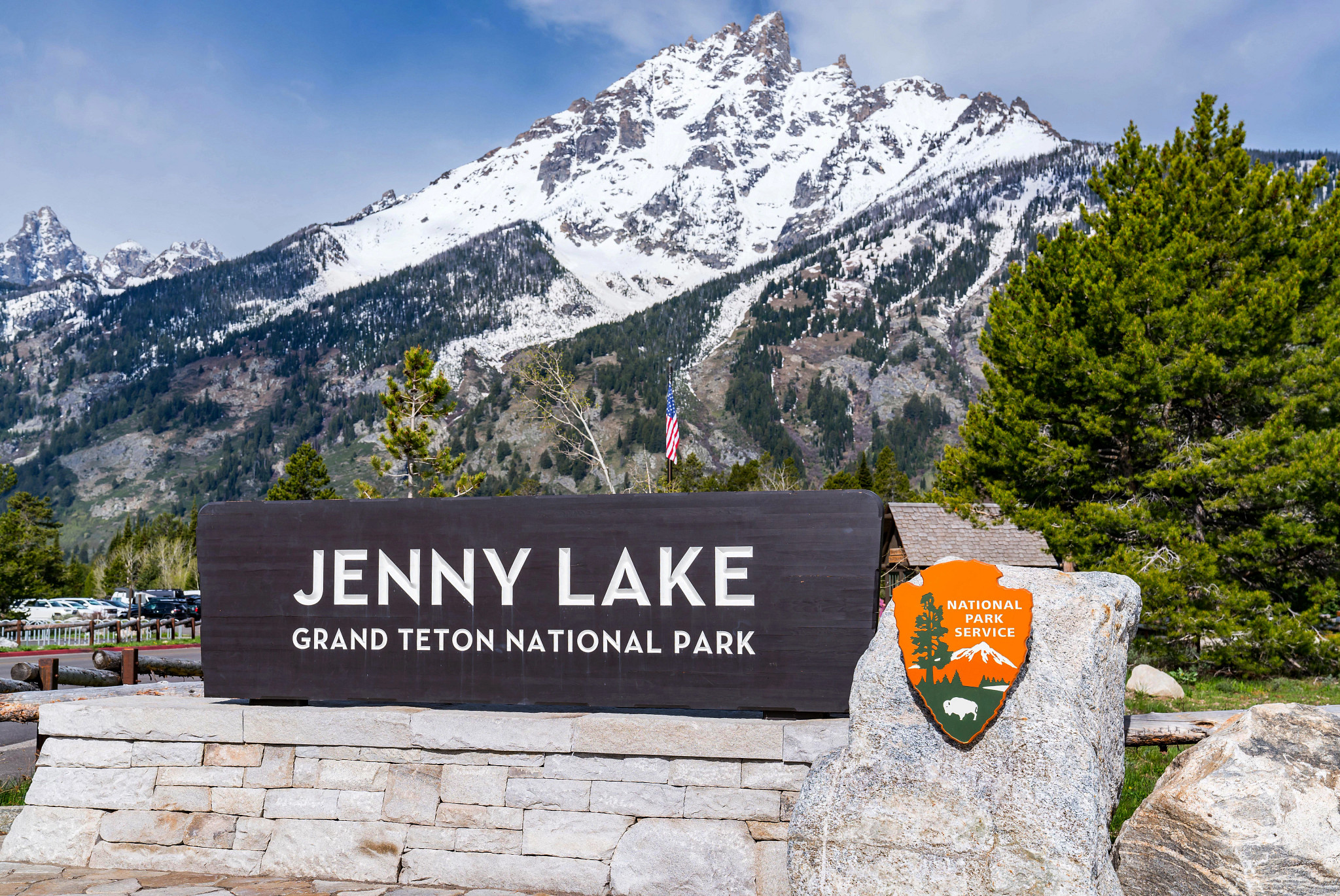 View of Jenny Lake sign at the Grand Teton National Park with mountain range in the background