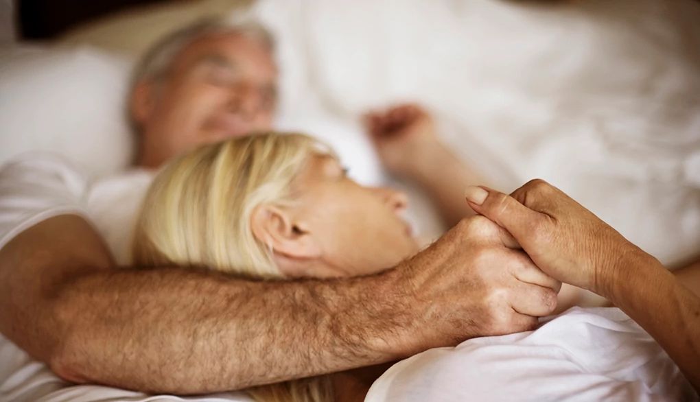 Making a close connection with your partner before bed may improve sleep A man and woman cuddling in a bed together
